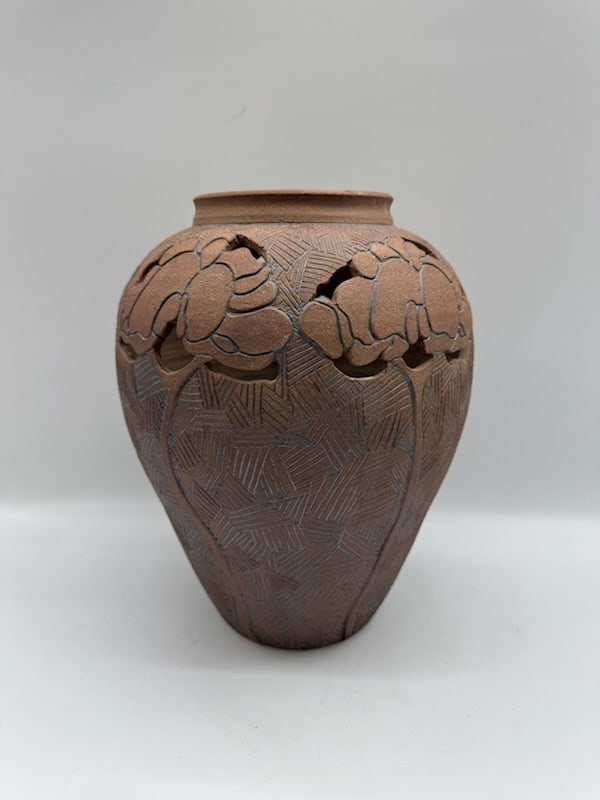 Studio Pottery Vase with Floral Design: Studio pottery vase featuring a textured surface and stylized floral design. The vase has a bulbous form with carved floral motifs around the upper portion and geometric patterns on the body. The piec