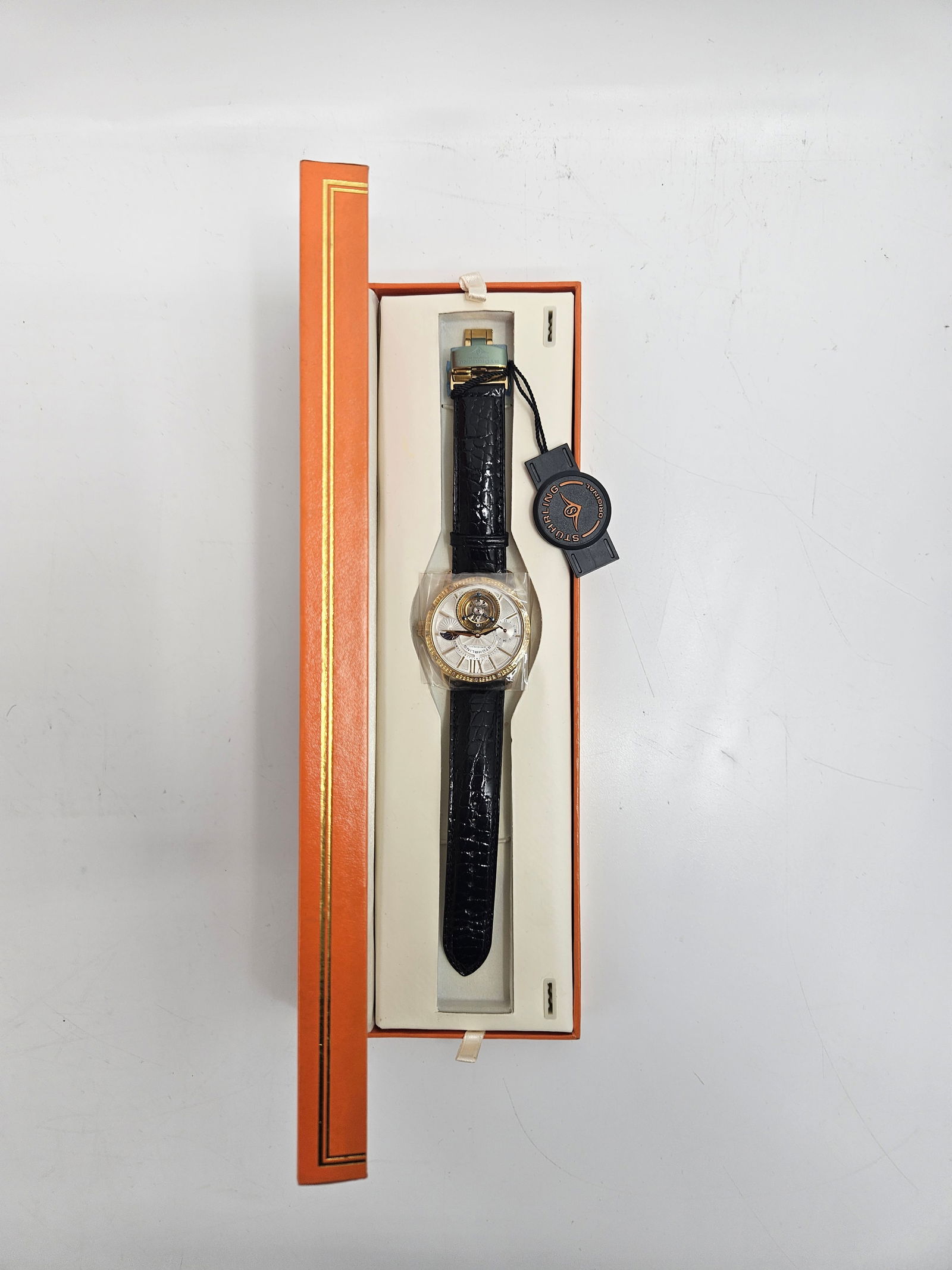 Stuhrling Original Tourbillon Automatic Wristwatch in Box: Elegant Stuhrling Original men’s wristwatch featuring a visible tourbillon movement, gold-tone case, Roman numeral dial, and black leather strap. Comes complete with original box, papers, and ta