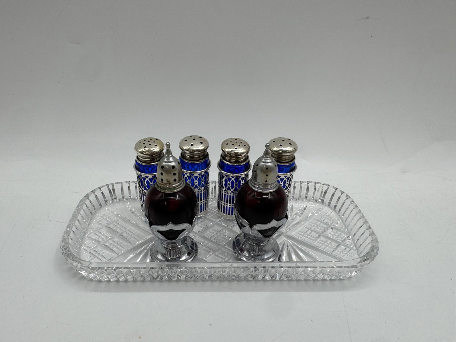 Crystal Tray with Salt and Pepper Shakers: Crystal tray with two larger salt and pepper shakers and four smaller shakers. Tray measures approximately 9 x 4 inches. Elegant set for dining.