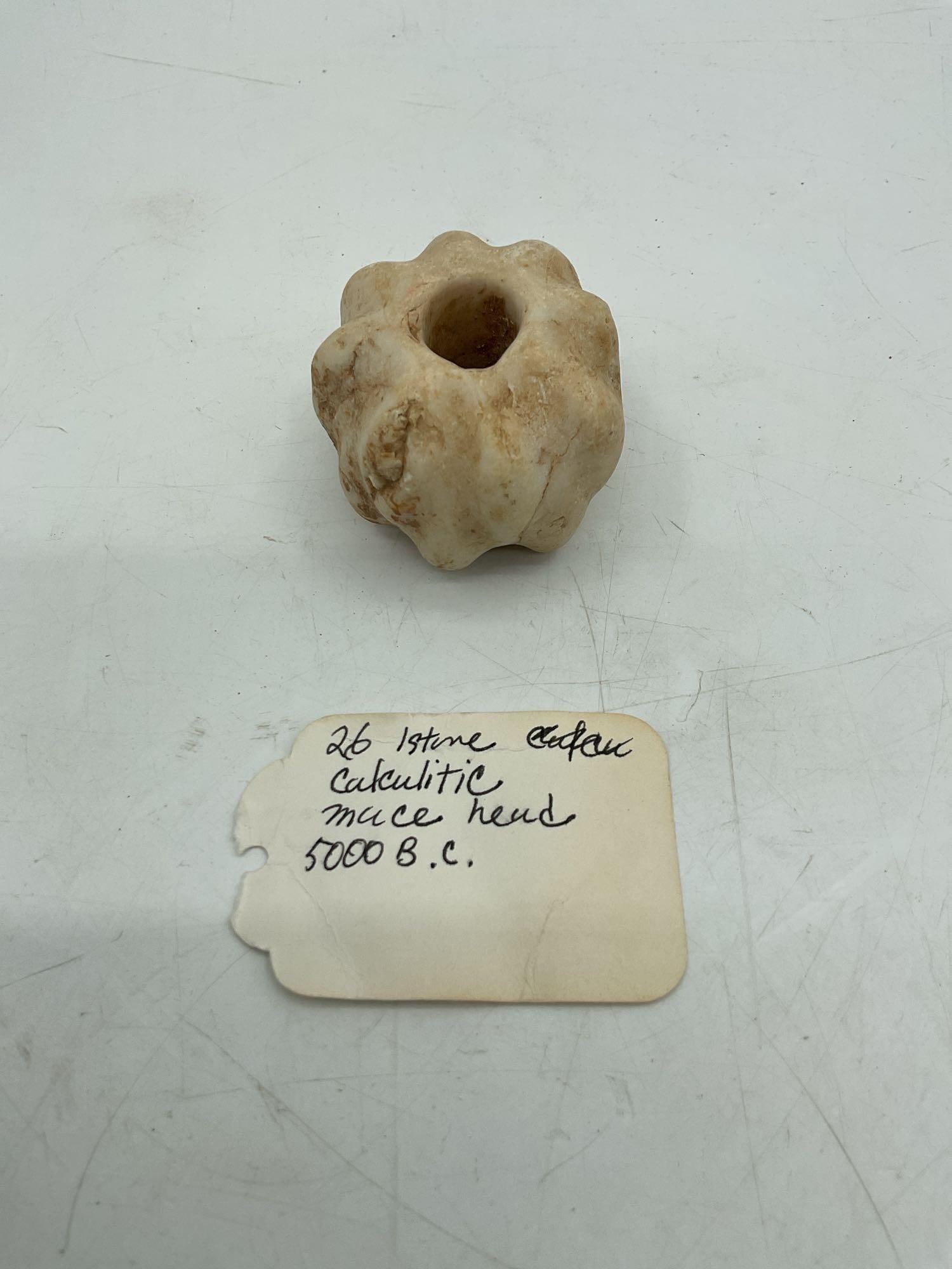 26 - Istone Calculitic mace head 5000 B.C.: Early ceremonial or functional mace head from the Chalcolithic period, carved in stone with a central perforation for hafting. Such items were used as symbols of authority or weapons, originating from