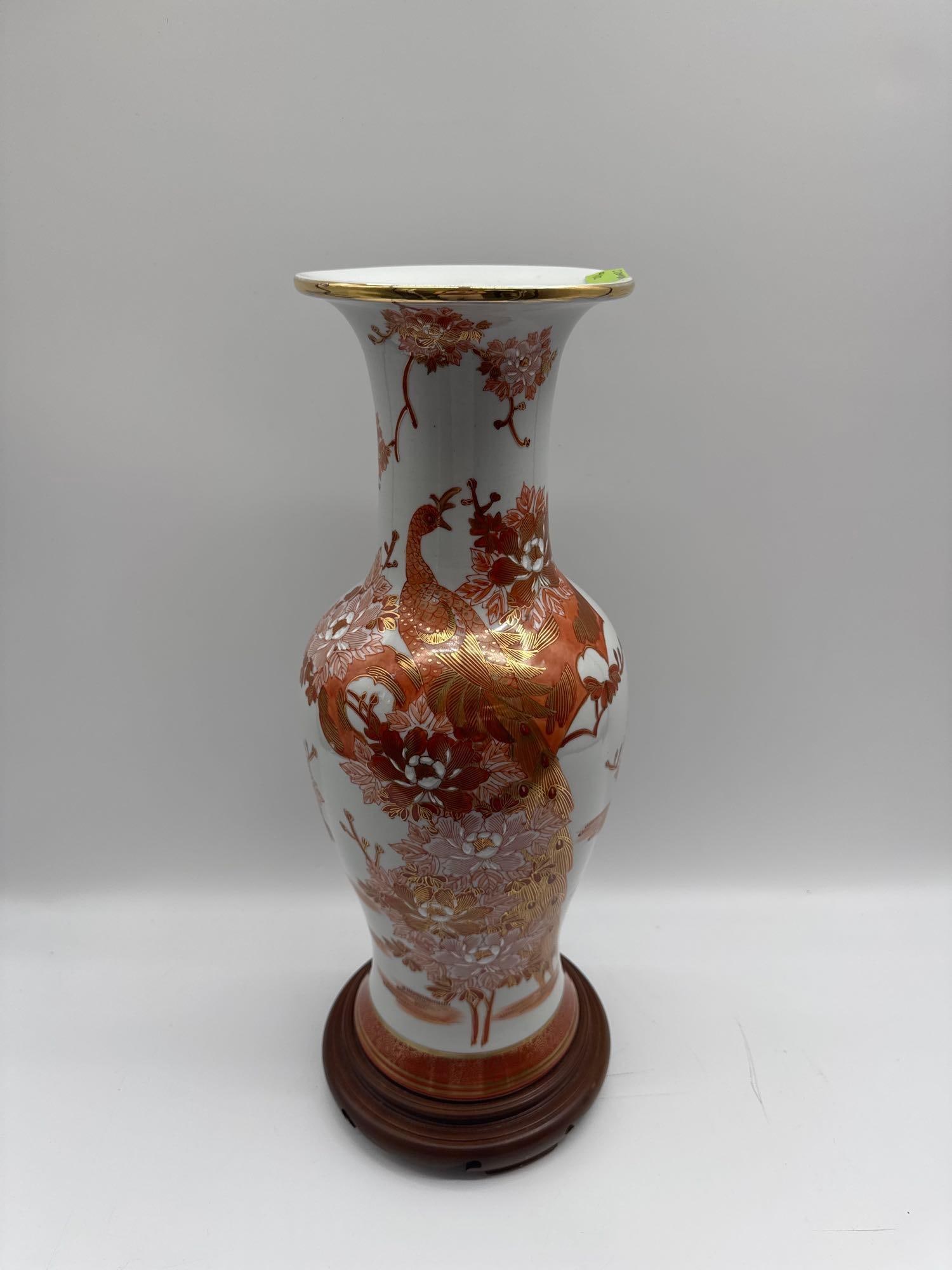 Porcelain Vase with Peacock and Floral Motif: A tall, flared porcelain vase finely decorated with intricate red and gold enamel designs. The central motif features a proud peacock surrounded by detailed blossoms and foliage, accented with gilt hi