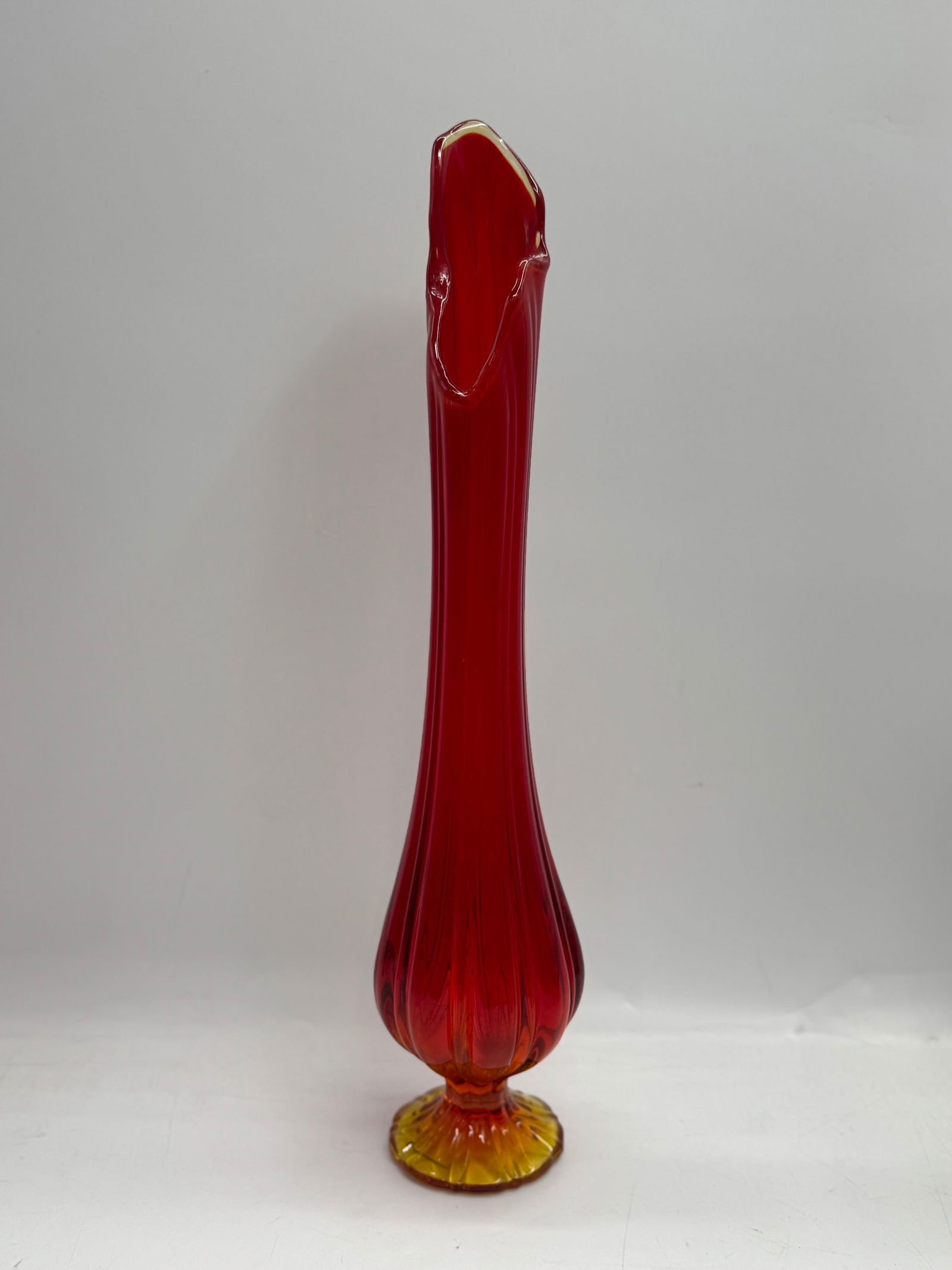Mid-Century Modern Red & Amber Glass Swung Vase: A striking mid-century modern glass swung vase featuring a vibrant red body and amber base. The vase stands approximately 21 inches tall and has a unique, elongated form with a flared top. The body is