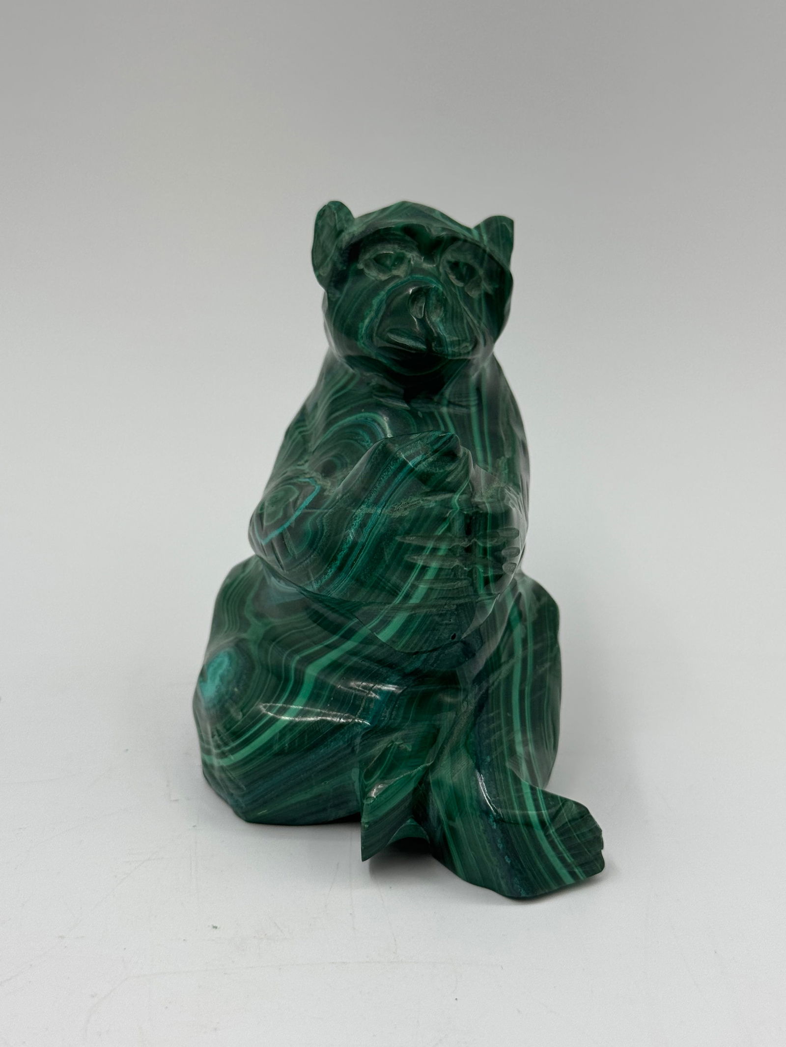 Malachite Bear Figurine: A carved malachite figurine depicting a bear in a reclining position. The stone exhibits characteristic green banding. Dimensions: 3.5 x 3 x 2 inches.