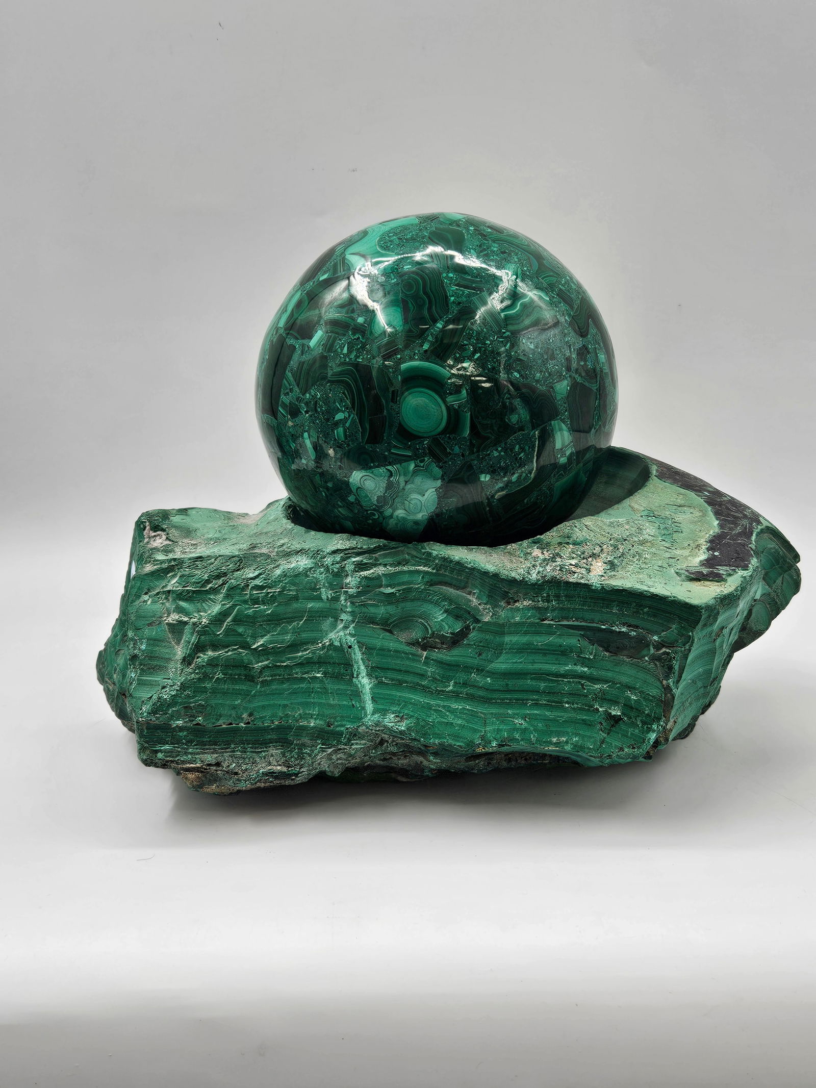 Malachite Sphere and Matrix: A malachite sphere, approximately 7 inches in diameter, resting in a carved malachite matrix. Overall dimensions are approximately 15 x 9.5 x 5 inches.