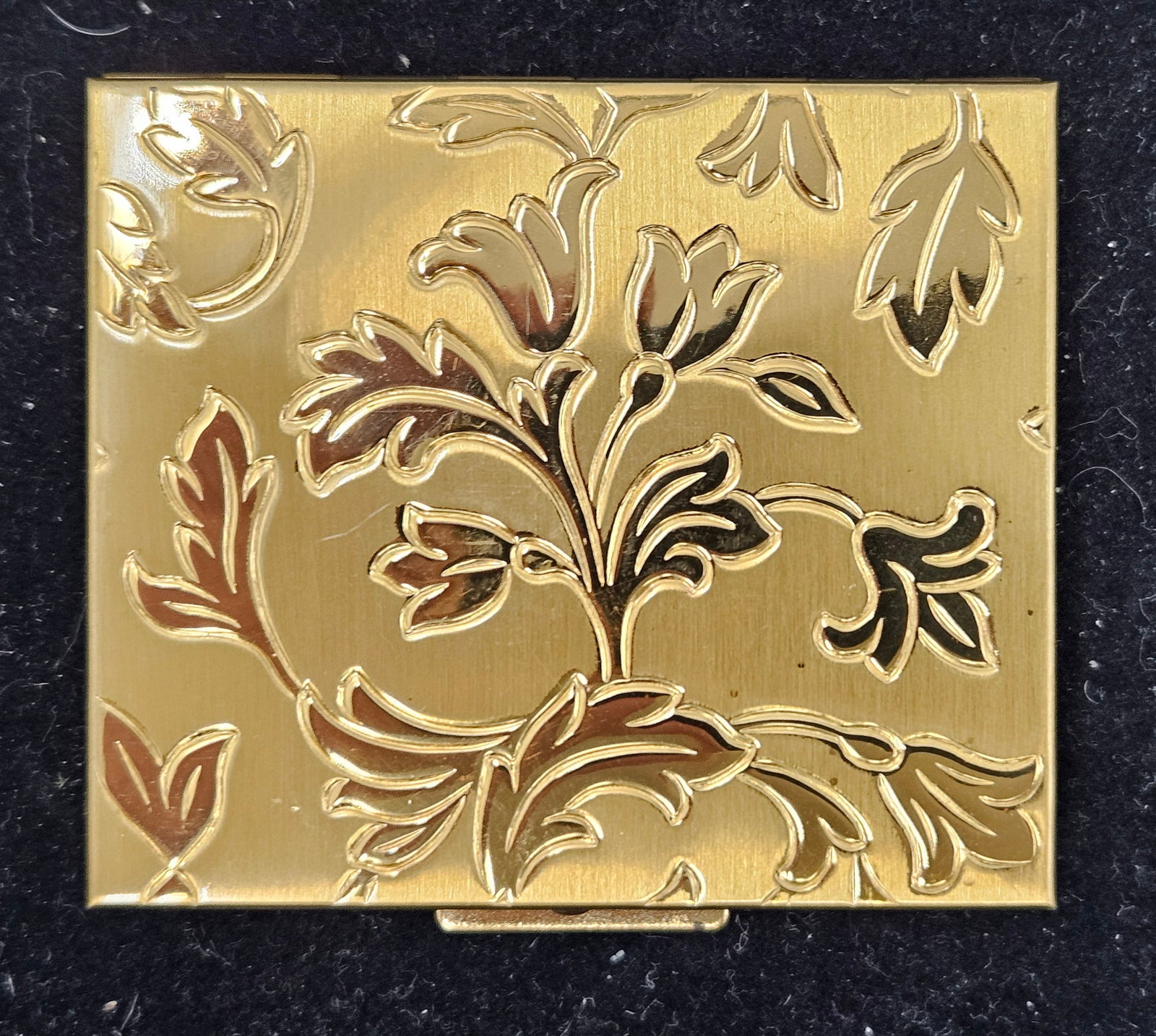 Vintage Brass Floral Petty Cash Box: A mid-century gold-tone petty cash holder featuring an embossed floral design on the lid and labeled interior compartments for coins. Dimensions: H: 3in W: 2.5in