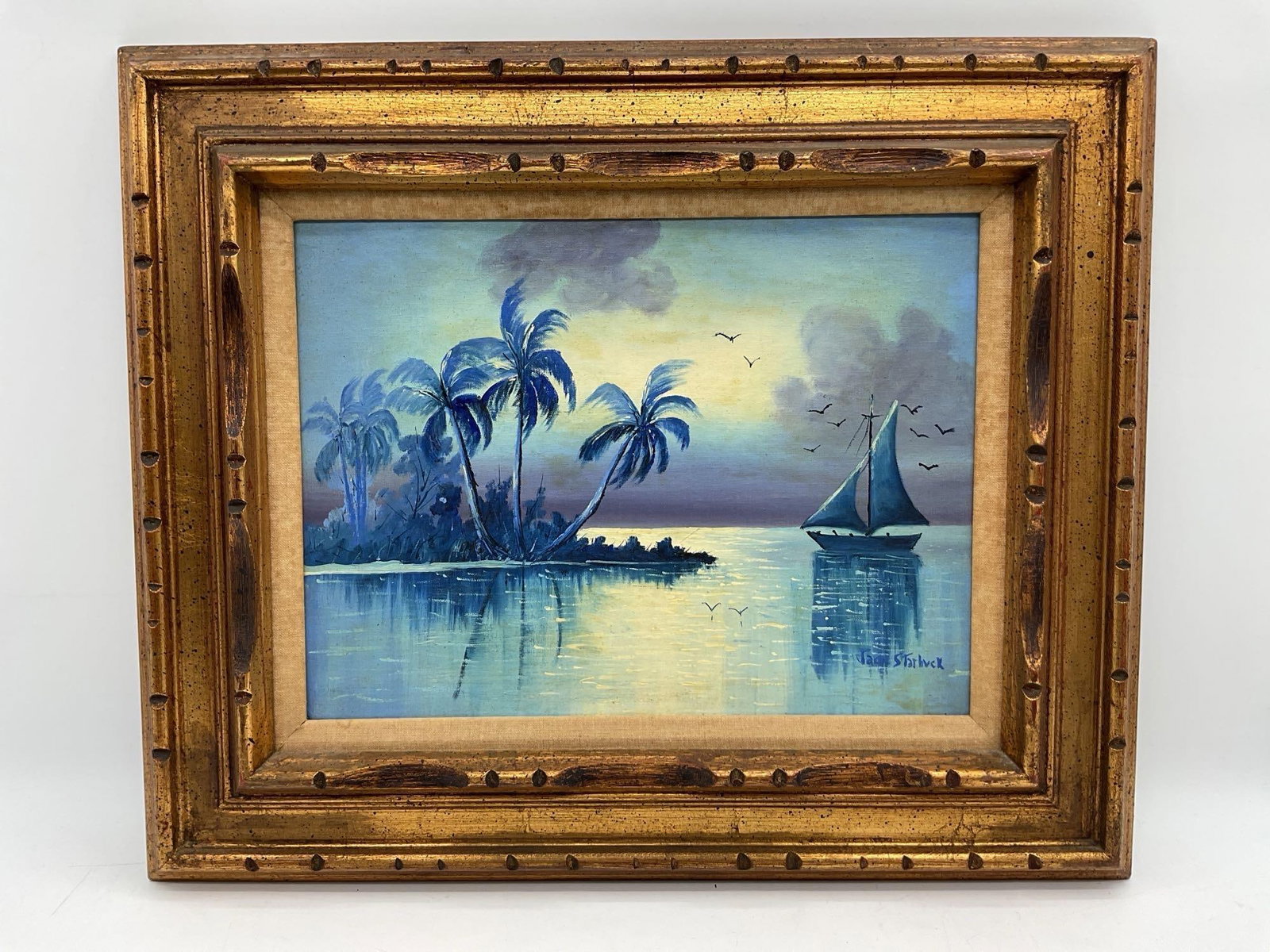 Jack Starbuck Florida Sunset Seascape: Original painting by Jack Starbuck depicting a tranquil coastal scene with sailboat, palms, and birds at sunset in soft blue and lavender hues Dimensions: H:20in L:24in Medium: Oil on canvas in carved