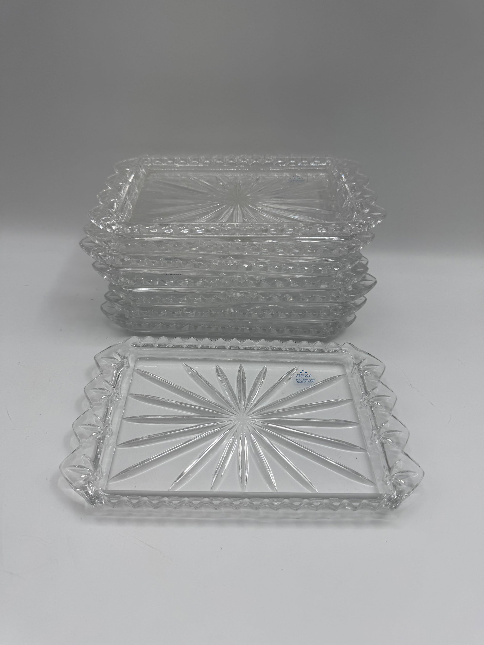 Set of 12 Irena Crystal Starburst Trays: Set of twelve Irena crystal trays. Each tray features a starburst design on the base and a scalloped edge. Marked "IRENA Hand Made Poland" on the front. Each tray measures approximately 6&qu
