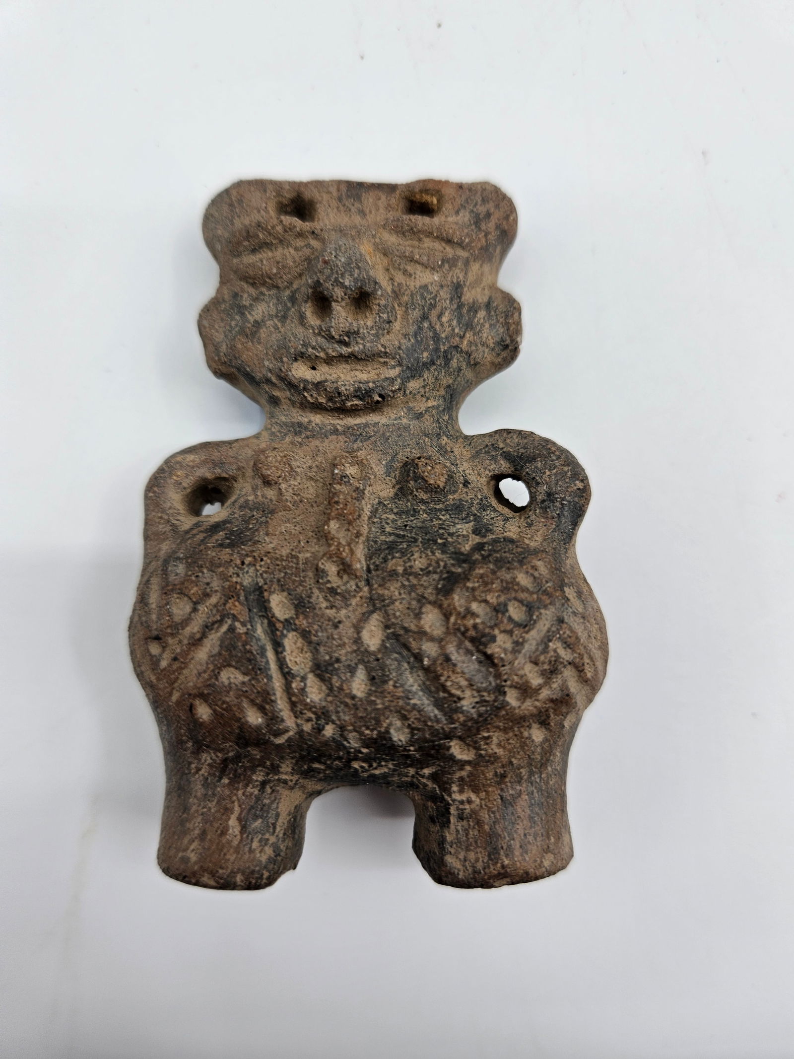 Pre-Columbian Pottery Stamp: A Pre-Columbian pottery stamp, possibly used for textile or body decoration. The stamp features a stylized animal or deity design with geometric patterns. The piece shows signs of age and wear, consis