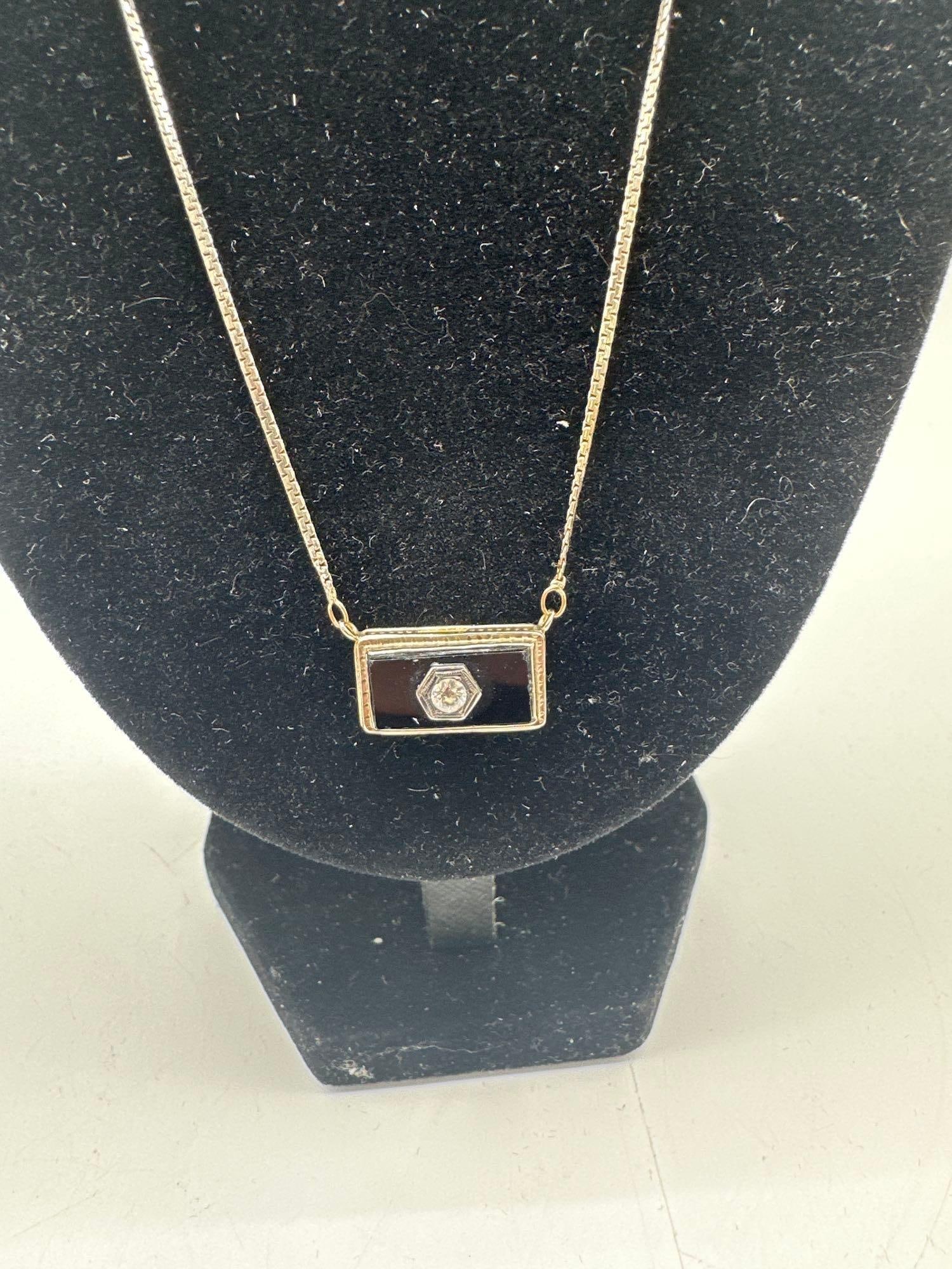Art Deco Style Pendant Necklace with Black Enamel and Clear Stone: Delicate rectangular pendant necklace featuring black enamel inlay with a central faceted clear stone set in a hexagonal frame. The pendant is bordered by a textured gold-tone bezel and hangs from a f