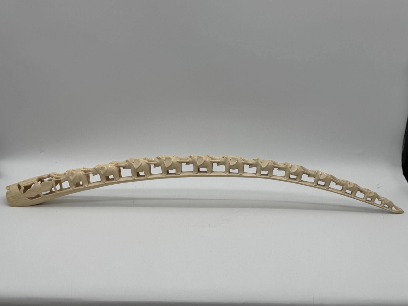 African Hand-Carved Elephant Row Sculpture – Row of Elephants: Dimensions: Beautiful long curved tusk-style sculpture carving, featuring a continuous procession of elephants marching along the length of the piece. Each elephant is individually detailed, giving th