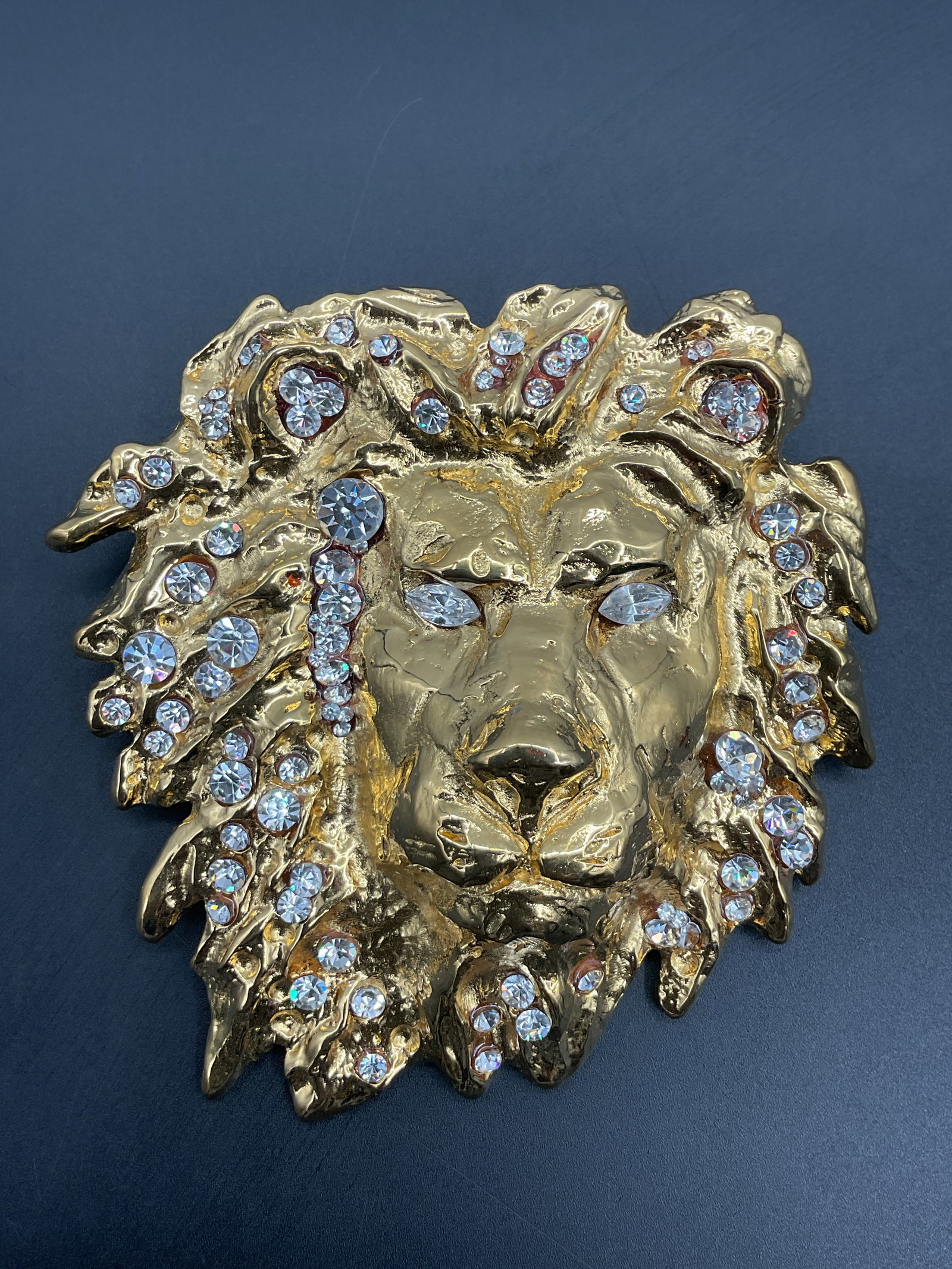 Katherine Baumann Swarovski Lion Head Belt Buckle: A Katherine Baumann belt buckle featuring a lion's head design, embellished with Swarovski crystals. Marked K. Baumann ©1993. Dimensions: 4 x 4 inches.