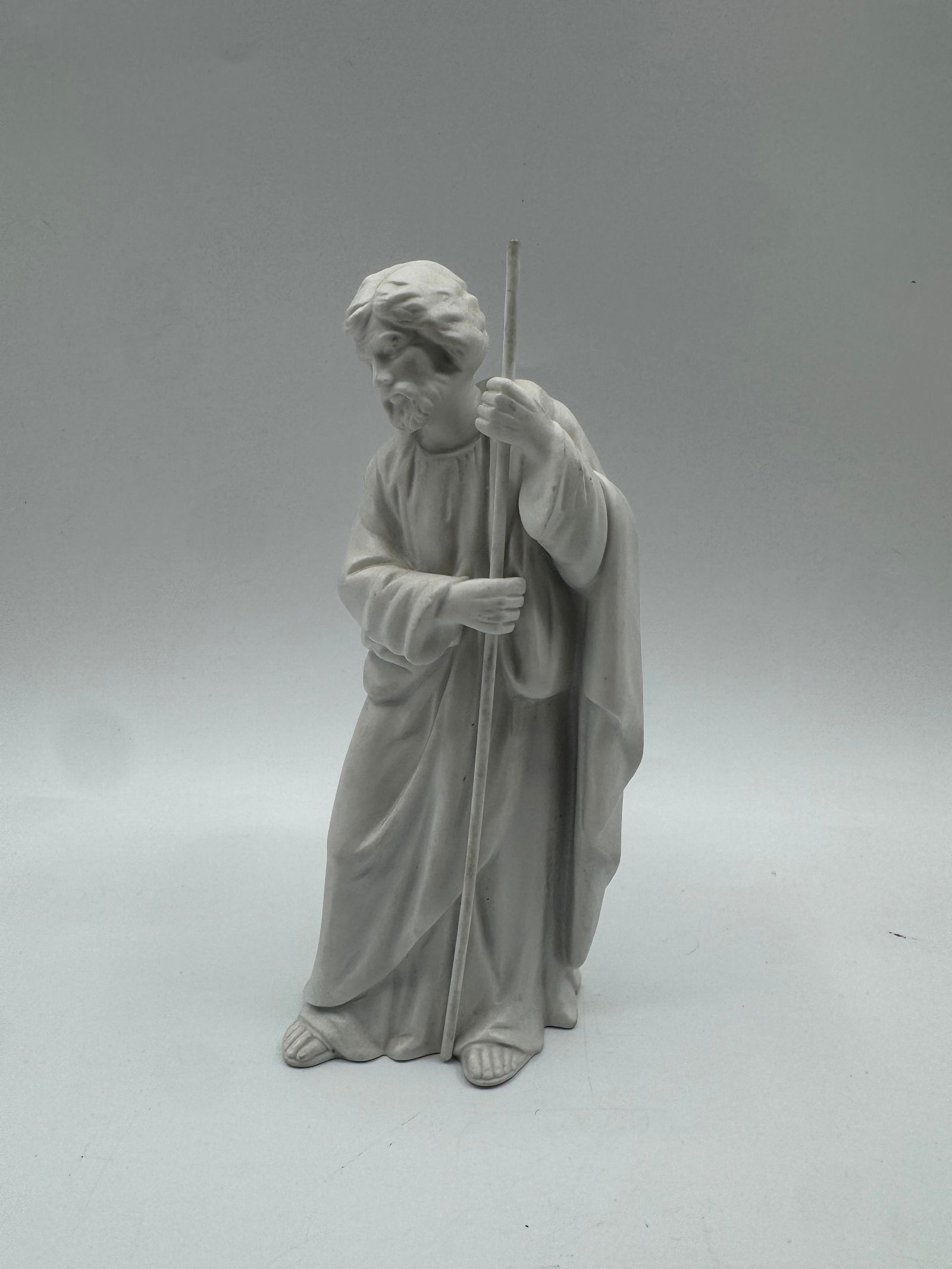 Vintage Bisque Joseph Figurine: Bisque figurine depicting Joseph holding a staff. Marked on the bottom. Dimensions: 8" H x 3" L x 3" W.