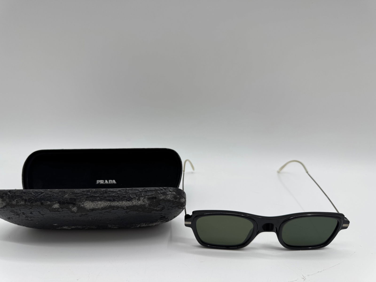 Prada Sunglasses with Case: Prada sunglasses featuring a black frame and silver-tone arms. Includes a Prada case.