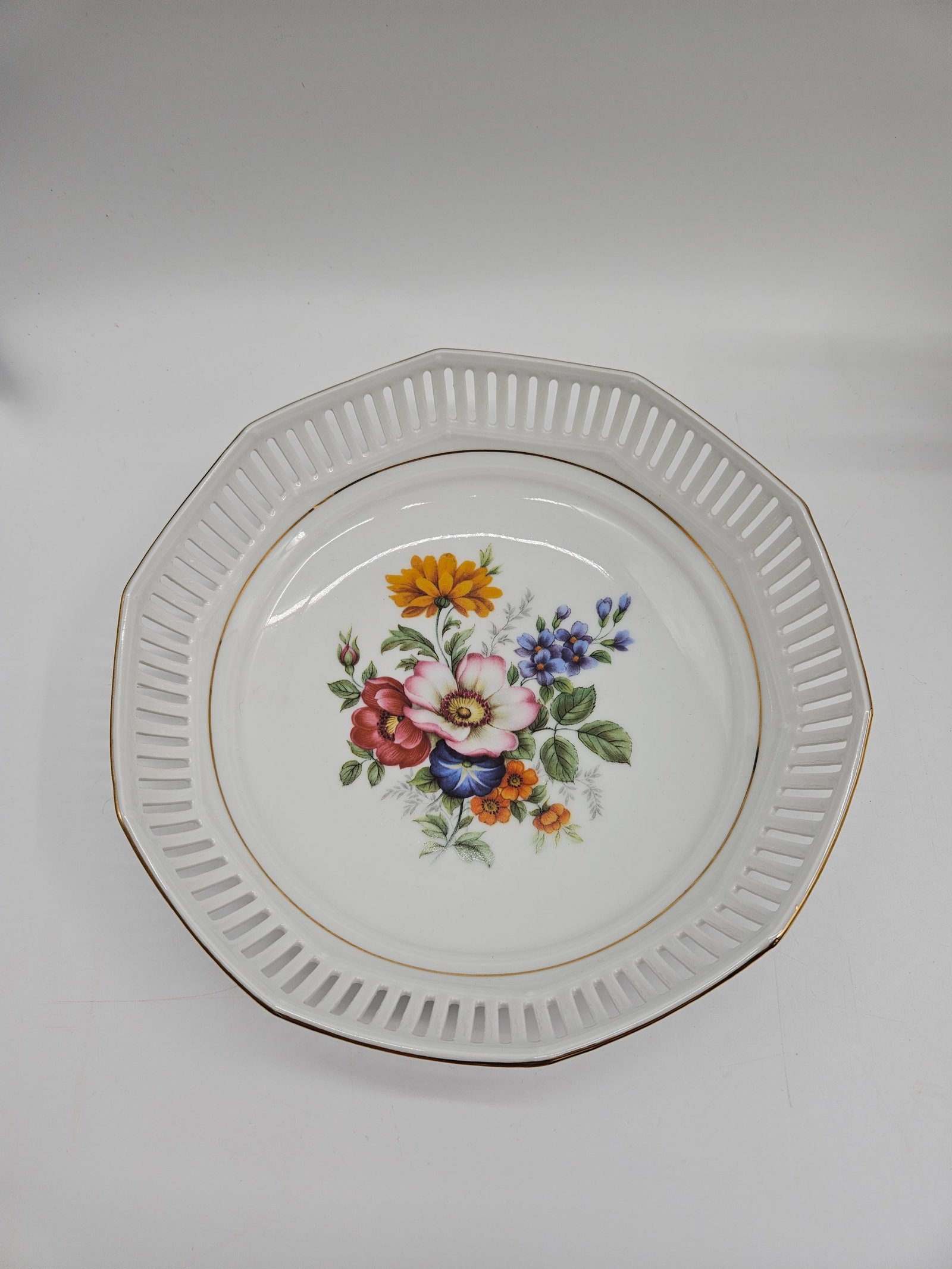 Schwarzenhammer Bavaria Reticulated Bowl: Schwarzenhammer Bavaria reticulated porcelain bowl. Features a central floral bouquet and a pierced rim with gilt accents. Approximately 2.5 inches high and 9 inches in diameter.