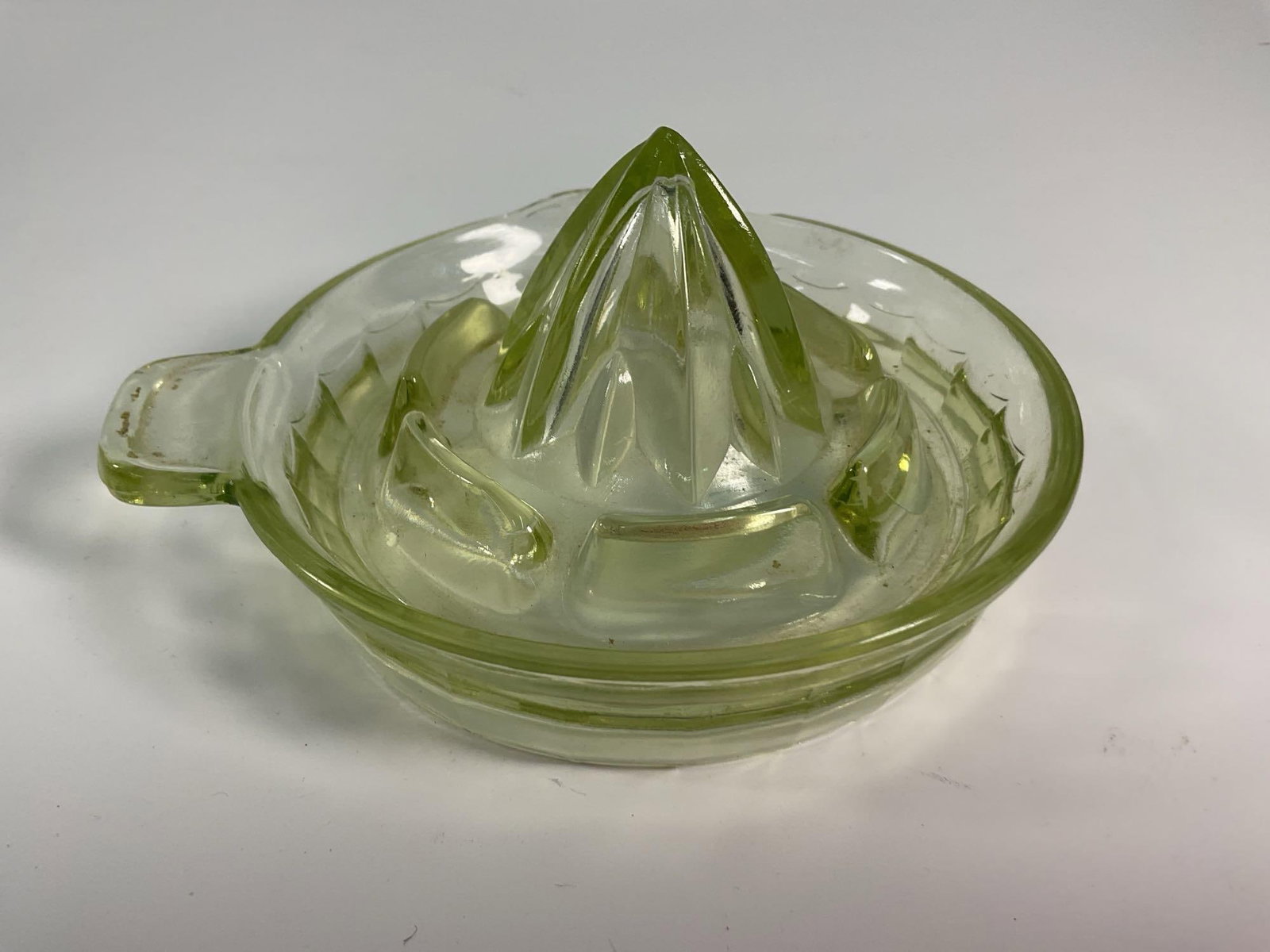 Green Depression Glass Juicer - Box 16: A classic vintage Depression glass citrus juicer in a subtle green tint, featuring a reamer-style top, a built-in strainer, and a spouted base for easy pouring. The attached handle provides convenienc