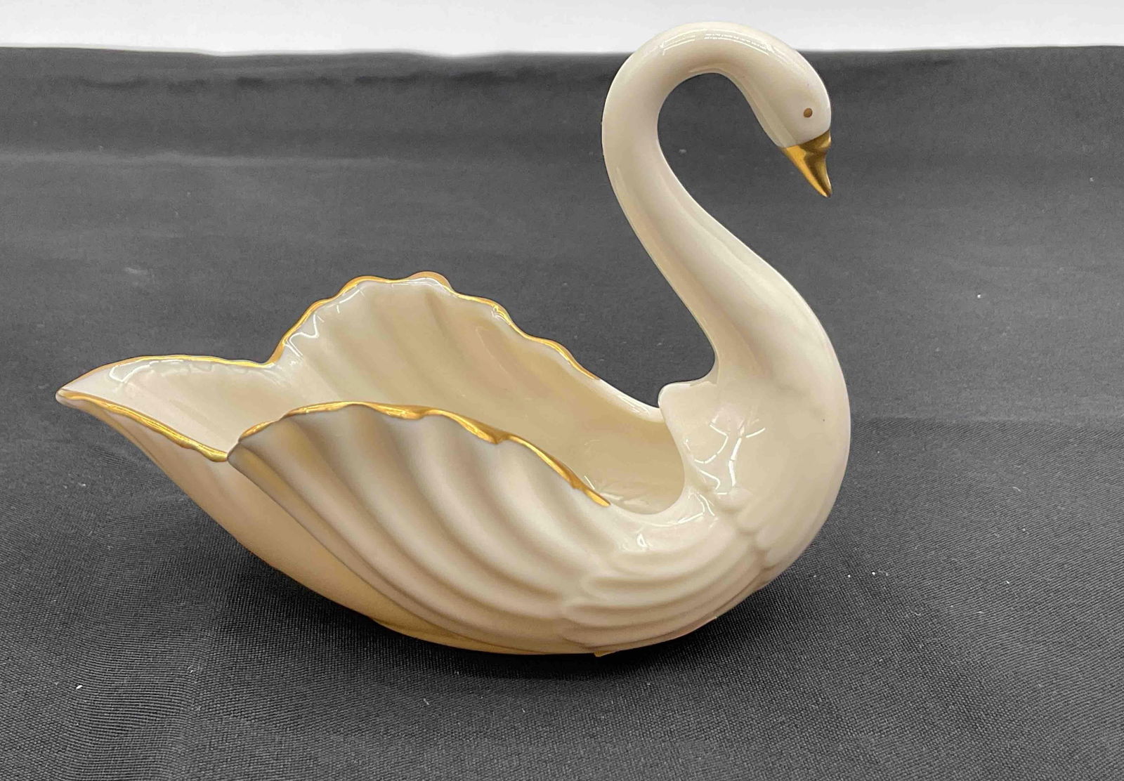 Lenox Porcelain Swan Figurine: Elegant cream porcelain swan with scalloped wings, hand decorated with 24k gold accents Medium: porcelain with gold detailing Dimensions: H4in L5in W3in