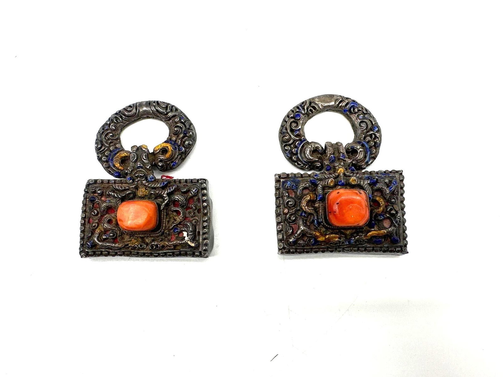 Pair of Tibetan or Himalayan Silver Toned Enamel Buckle Clasps with Coral Inset:  Ornate vintage buckle clasps featuring repoussé silverwork with colorful enamel detailing in red, blue, and yellow. Each rectangular section is centered with a faux or real coral cabochon