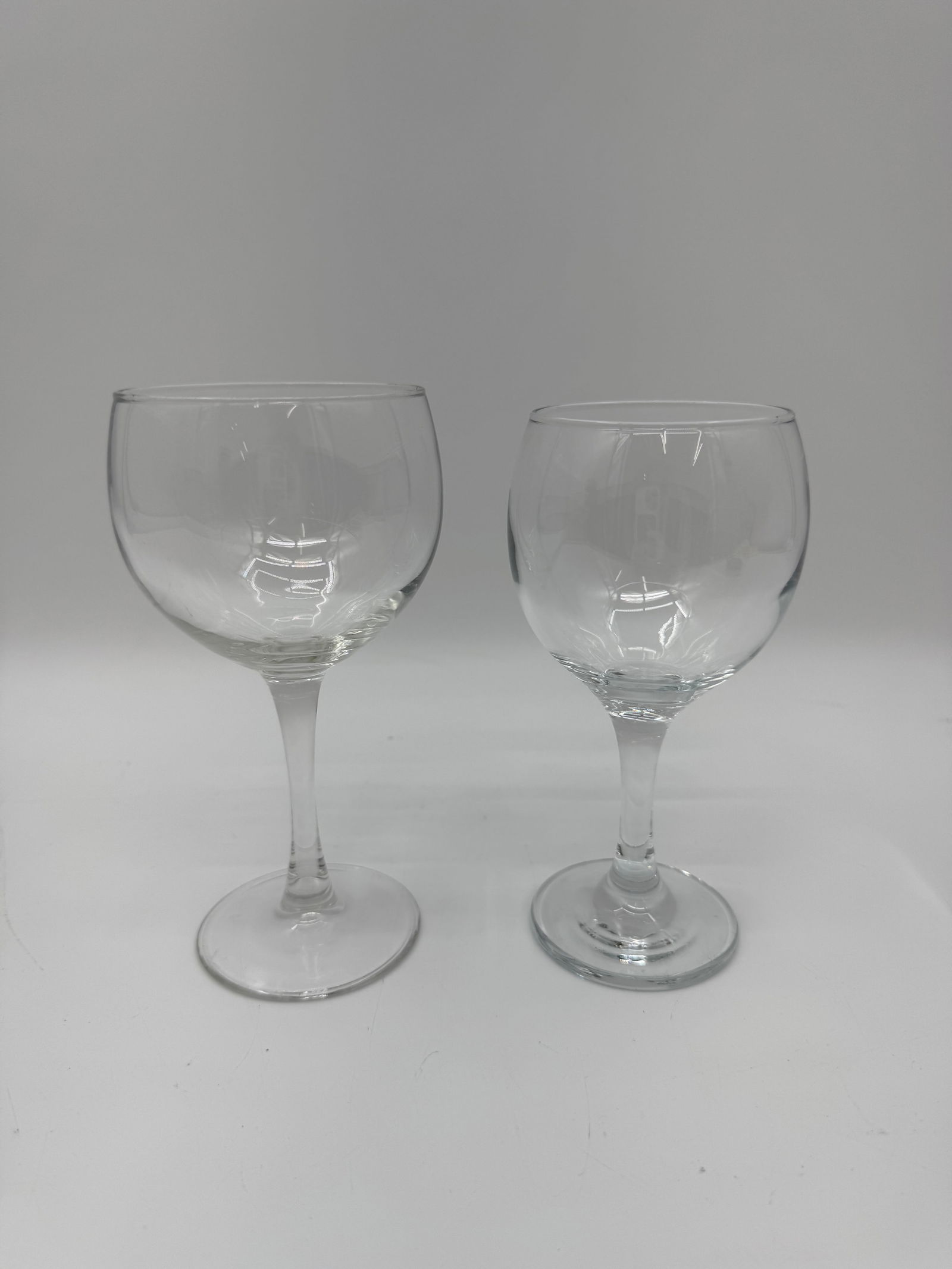 Pair of Clear Glass Goblets: Simple and elegant pair of clear glass goblets featuring rounded bowls and short stems. Perfect for everyday use or casual entertaining with classic appeal.