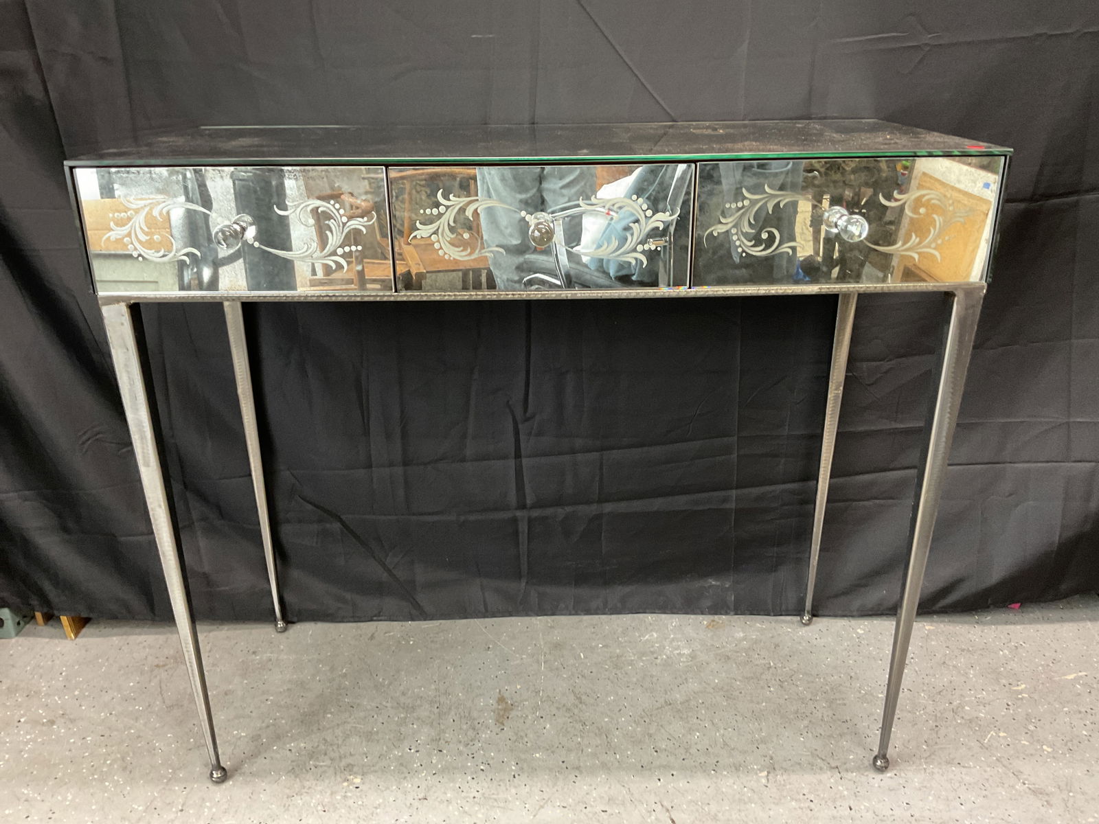Mirrored Console Table with Etched Floral Design: Stylish venetian mirrored console table featuring three drawers with etched floral designs and crystal-style knobs. Supported by slender metal legs, combining elegance and modern sophistication.1