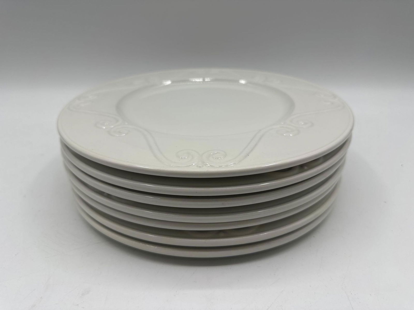 White Embossed Porcelain Dinner Plate Set - Euro Ceramica Portugal: Elegant white porcelain plate set featuring a raised floral and scrollwork pattern around the rim, suitable for formal dining. Dimensions: H:0.5in L:11in W:11in