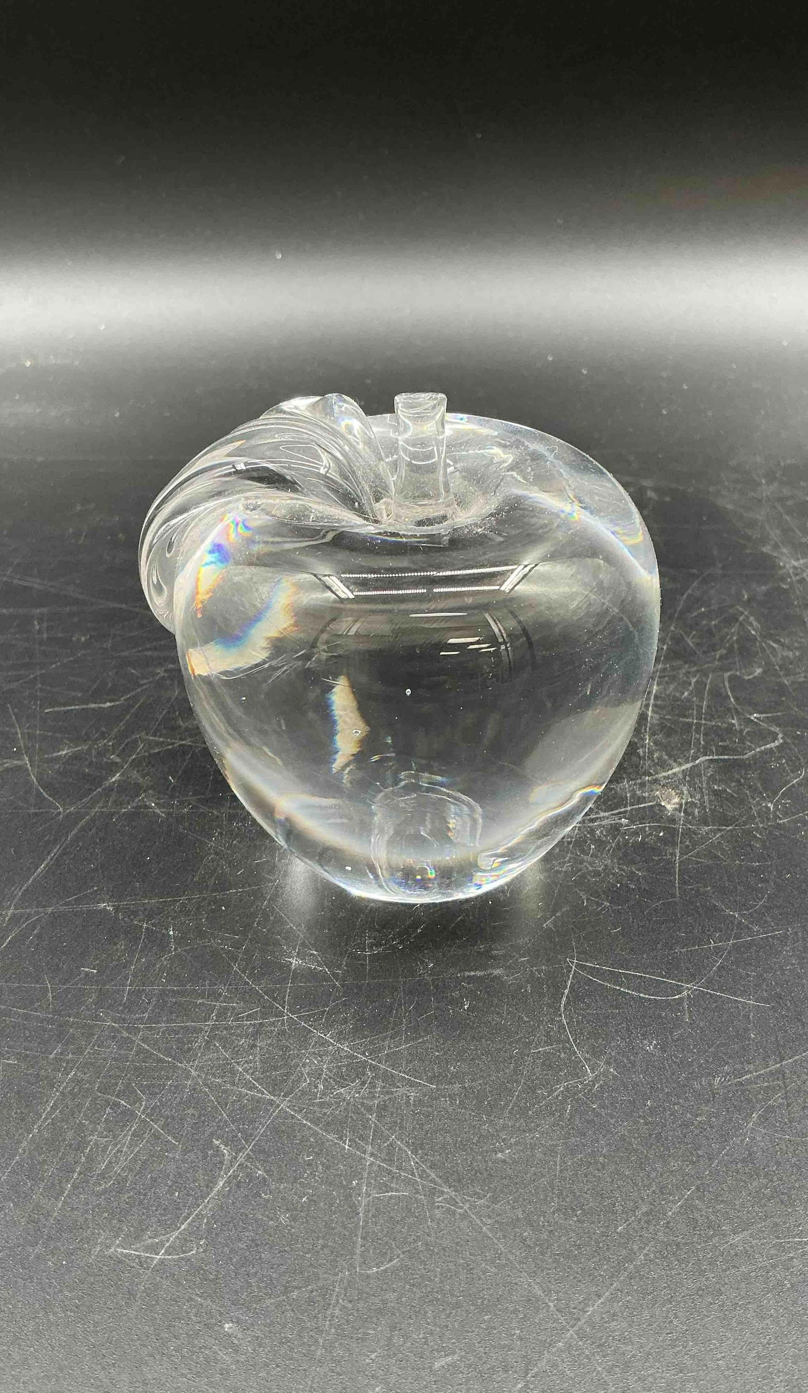 Clear Glass Apple Paperweight:  Elegant clear blown glass apple with a delicately curled stem and leaf design. Smooth and polished, this decorative piece can serve as a paperweight or collectible accent.Medium: Hand-blown clea