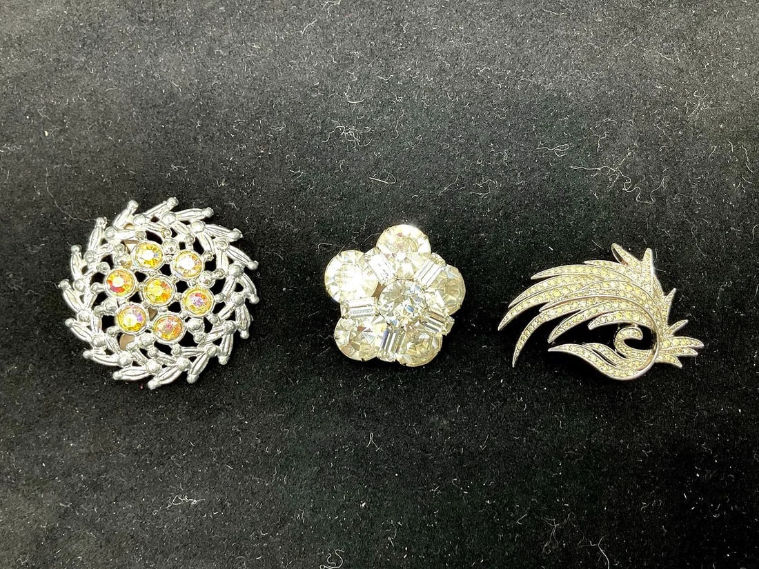 Group of vintage rhinestone brooches: Includes a floral brooch with yellow and clear stones, a silver-tone feather brooch, and a four-stone cluster brooch Dimensions: assorted sizes Medium: Rhinestones and silver-tone metal