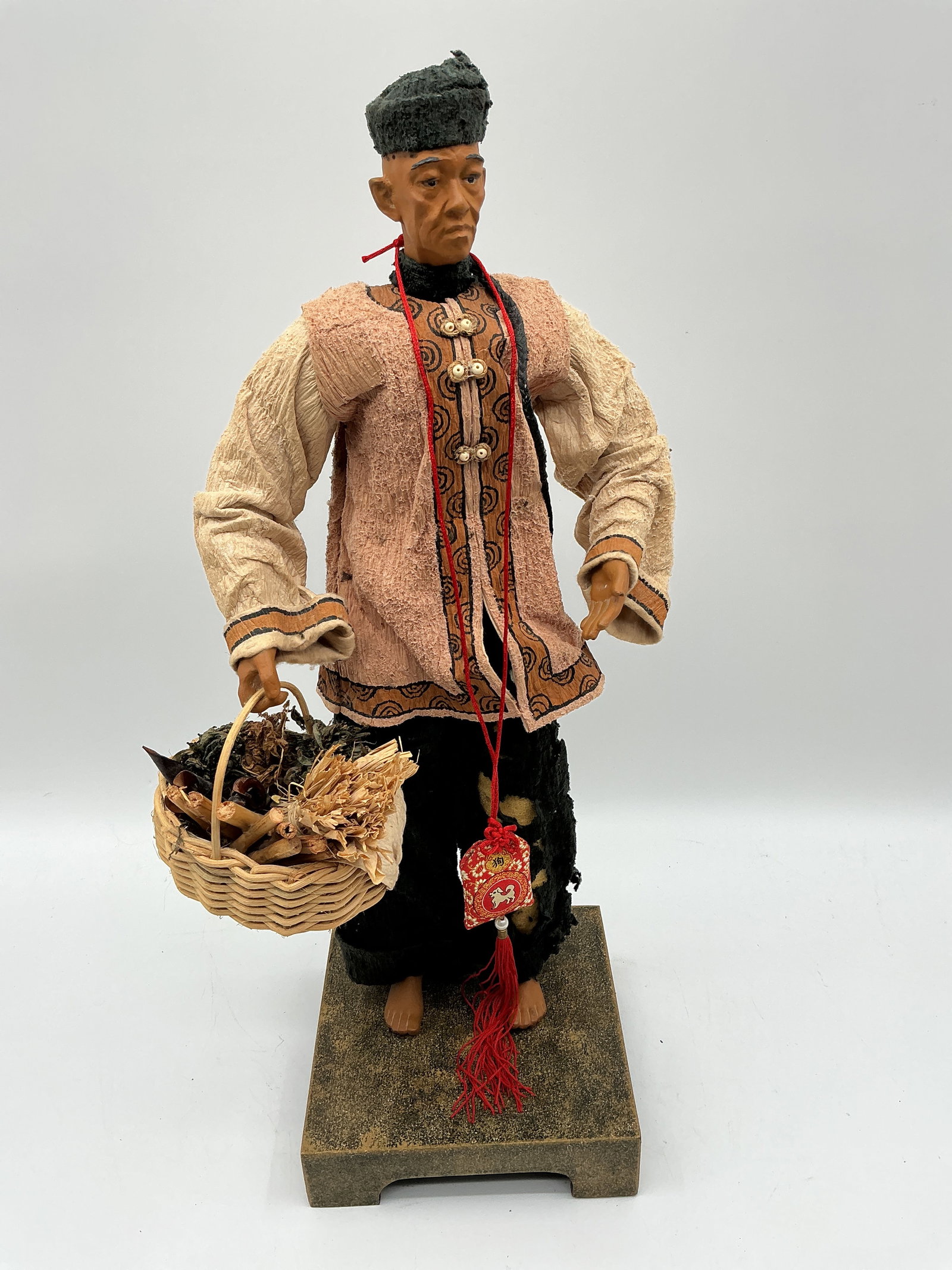 Asian Farmer Figurine with Basket: Handcrafted figurine depicting an elderly Asian farmer wearing traditional attire and holding a woven basket filled with gathered goods. Features detailed facial carving, embroidered fabric clothing,