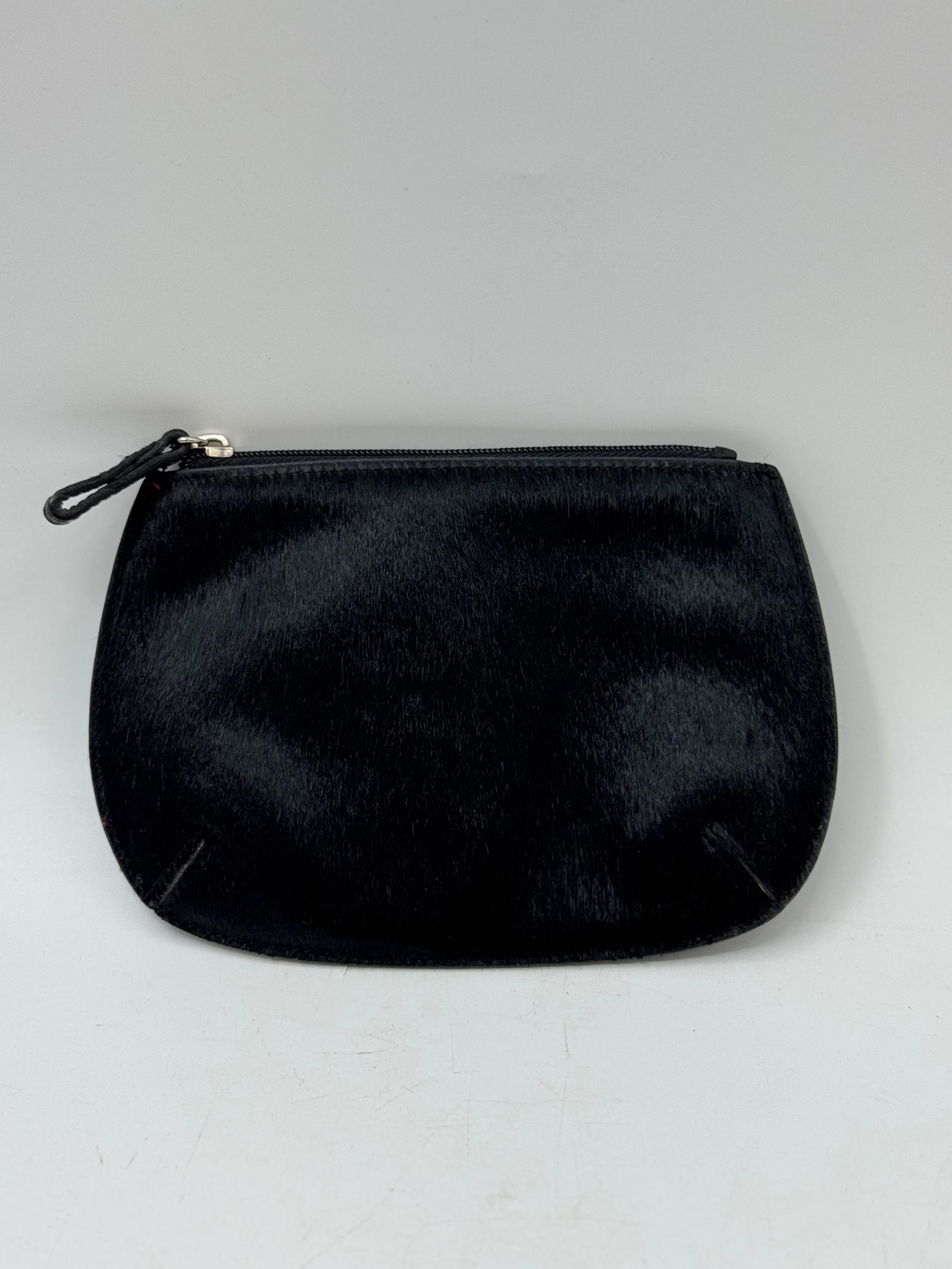 Black Haircalf Pouch: Black haircalf pouch with zip closure. Approximate dimensions: 8 x 5.5 inches. Ideal for small essentials.