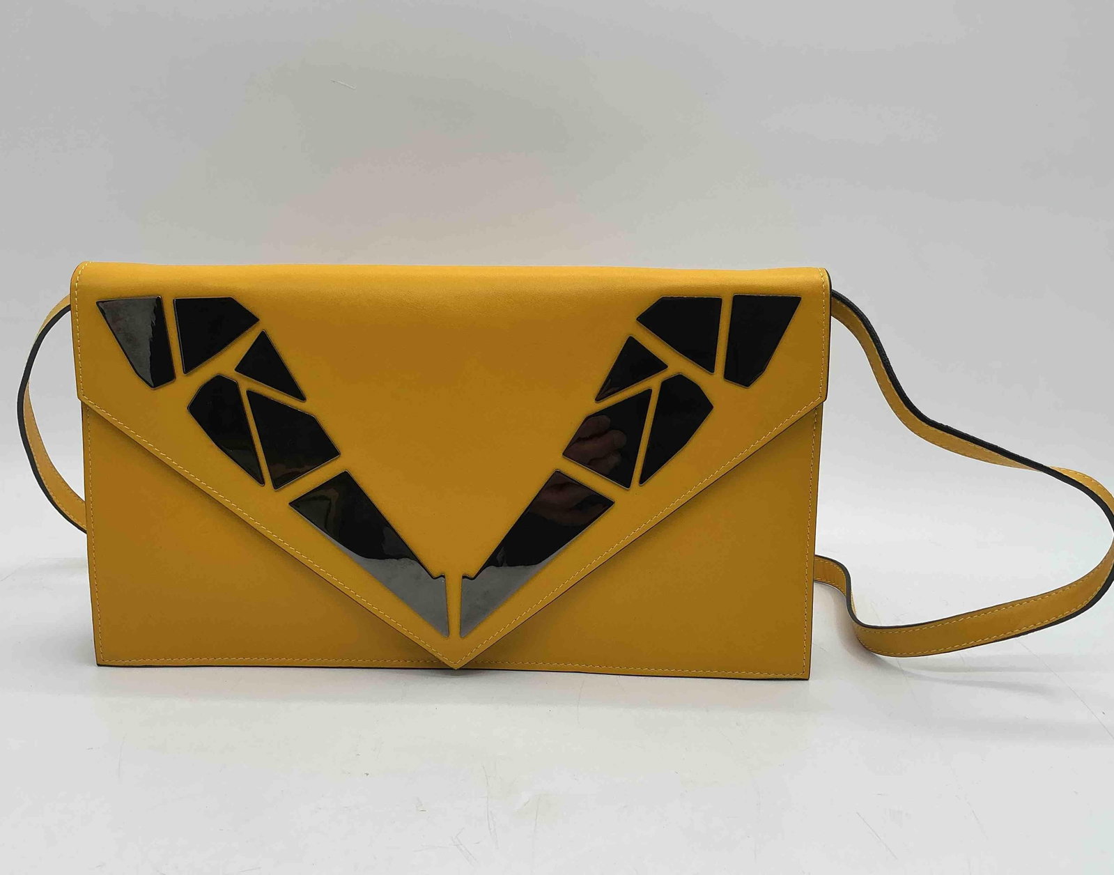George Angelopoulos Yellow Leather Clutch: Stylish yellow leather clutch by George Angelopoulos, featuring mirrored geometric inlay design on the front flap and a matching leather wrist strap. Interior includes a zip pocket and designer label,