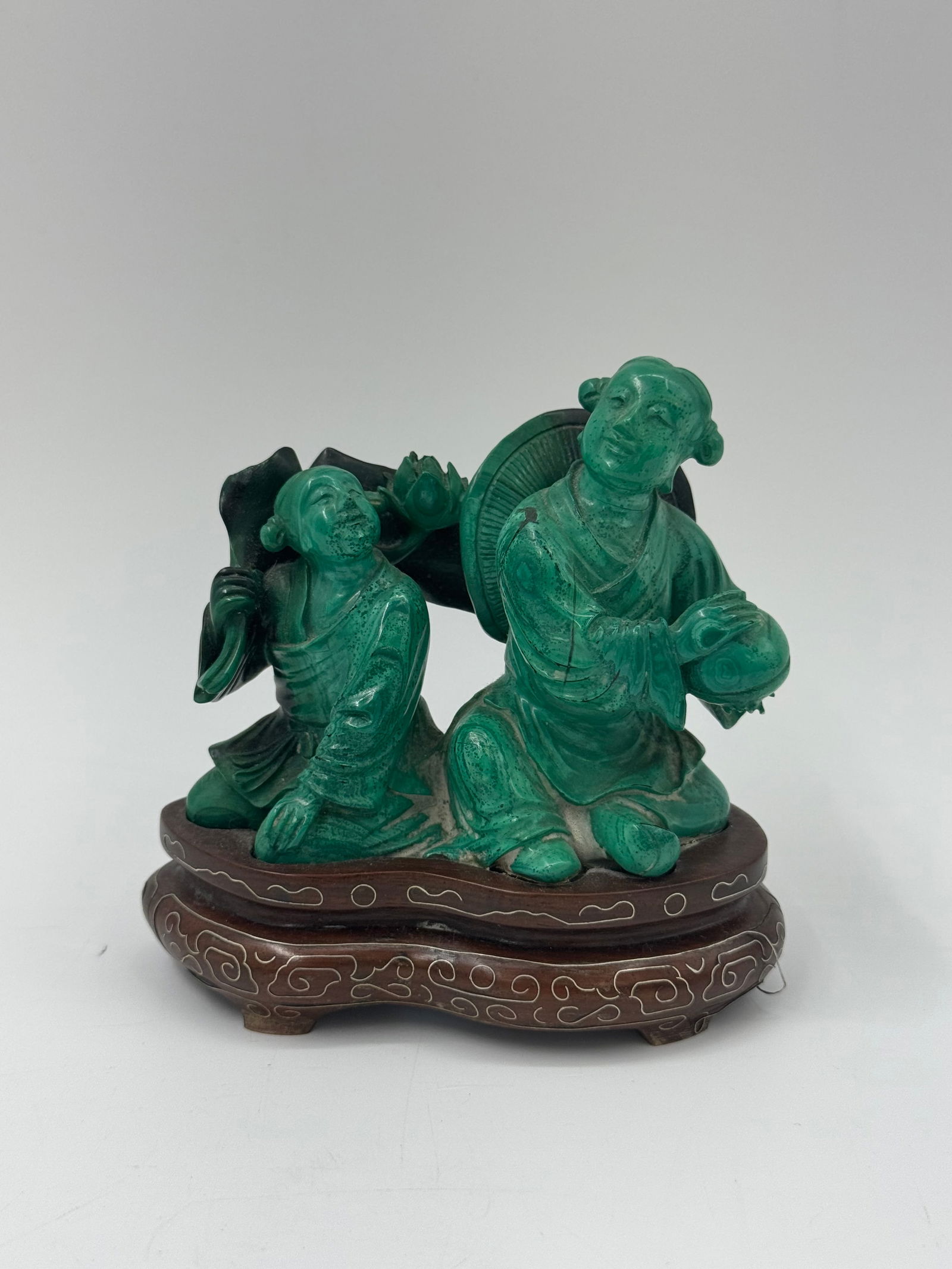 Chinese Carved Malachite Figure on Stand: A carved malachite figure depicting a man with a hat and a circular object, mounted on a decorative wooden stand. Dimensions: 4.5 x 4.5 x 2 inches.