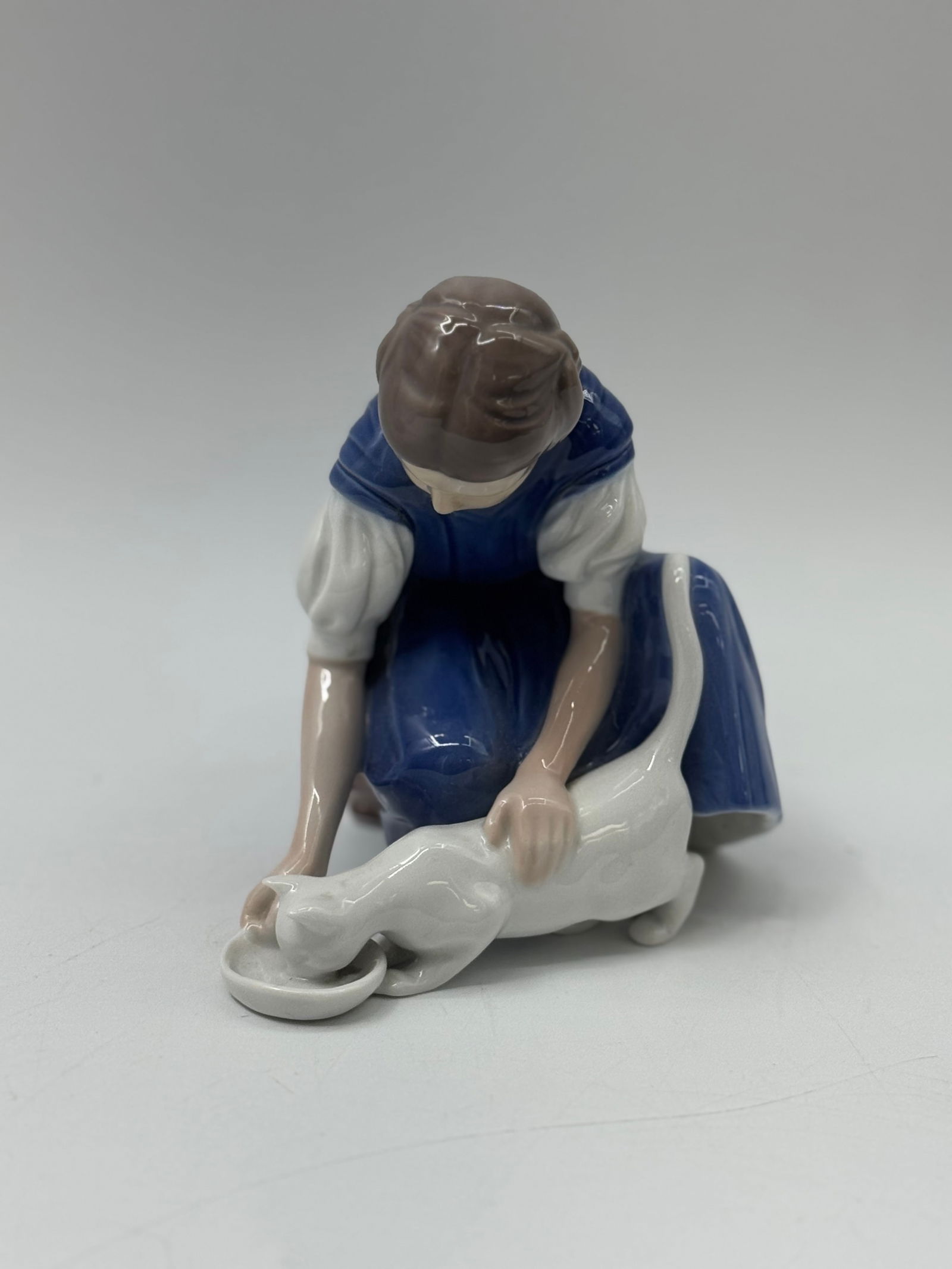 Bing & Grondahl Figurine - Girl with Cat: Bing & Grondahl figurine depicting a girl kneeling and offering a cat a bowl of food. Marked on the underside. Measures approximately 5 x 6 inches.