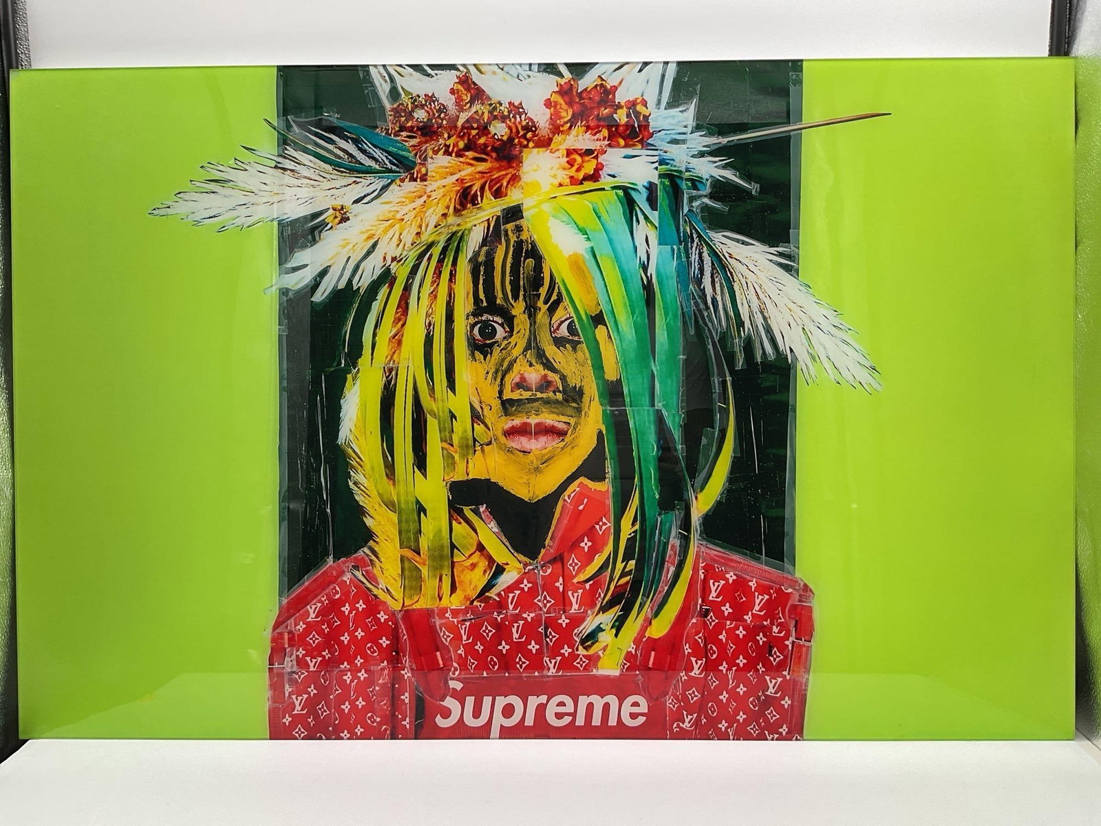 Supreme Warrior by Carlos Felix (Mexico, B. 1981): Vibrant contemporary collage featuring a masked figure adorned with feathers and tribal-like facial paint, juxtaposed with bold branding from Supreme. The neon green and red color blocks create a stre