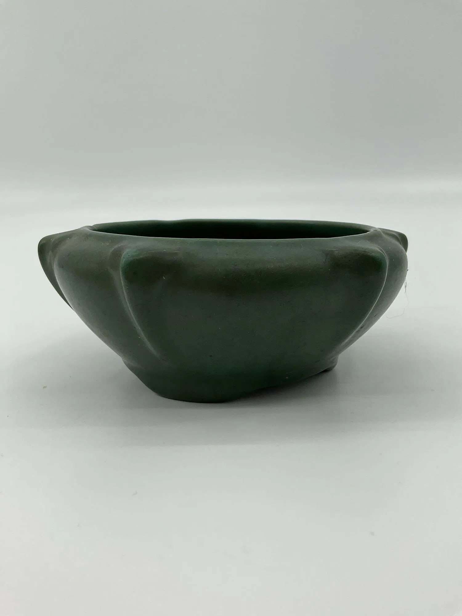Matte Green Art Pottery Bowl: A small shallow bowl with a rounded body and subtle lobed edges, finished in a deep matte green glaze. The understated design and surface treatment suggest early to mid 20th century American art potte