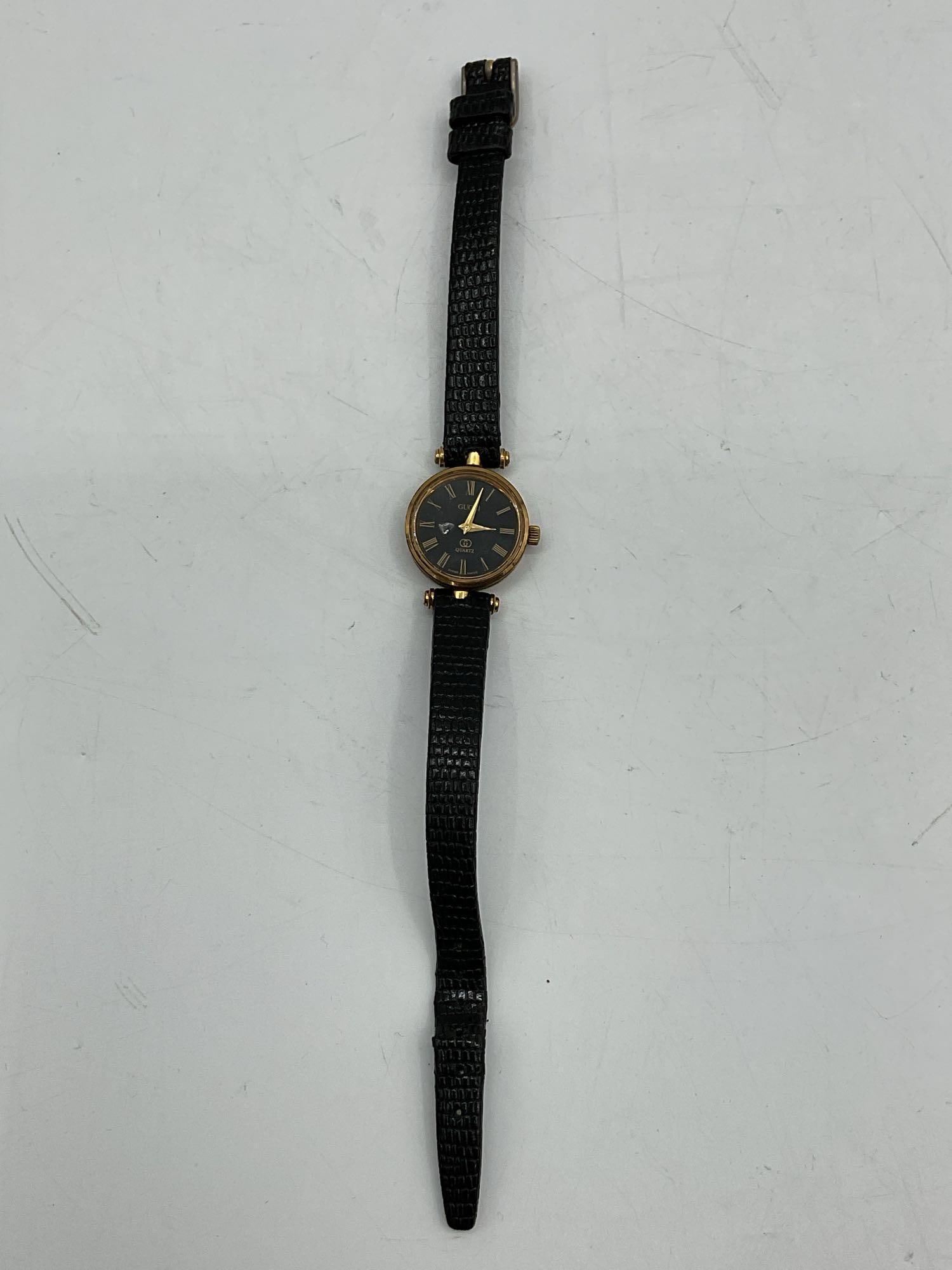 Vintage Gucci Quartz Ladies Watch: Classic Gucci women's wristwatch featuring a sleek black leather strap and a round gold-tone bezel. This vintage timepiece showcases the iconic elegance and understated luxury of Gucci. Dimensions