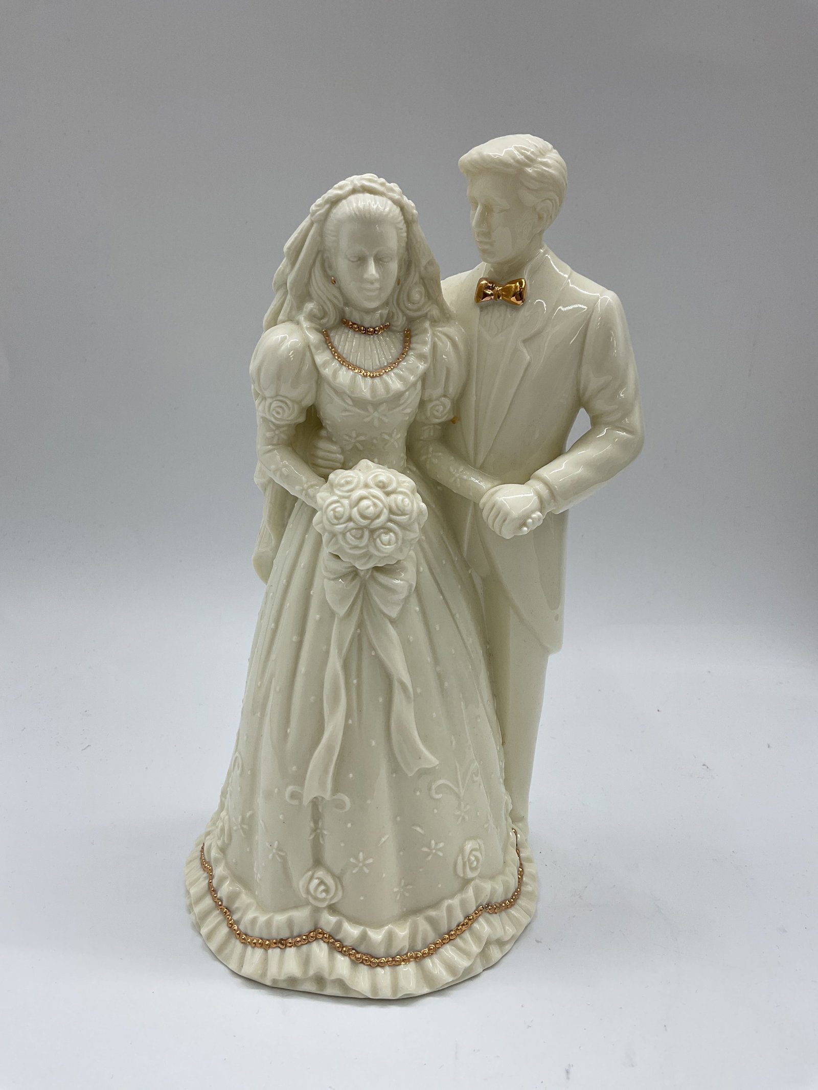 Lenox Bride and Groom Figurine: Intricately detailed Lenox ivory porcelain figurine featuring a bride and groom in formal wedding attire. The design includes gold trim accents on the bride’s gown and the groom’s bow tie.