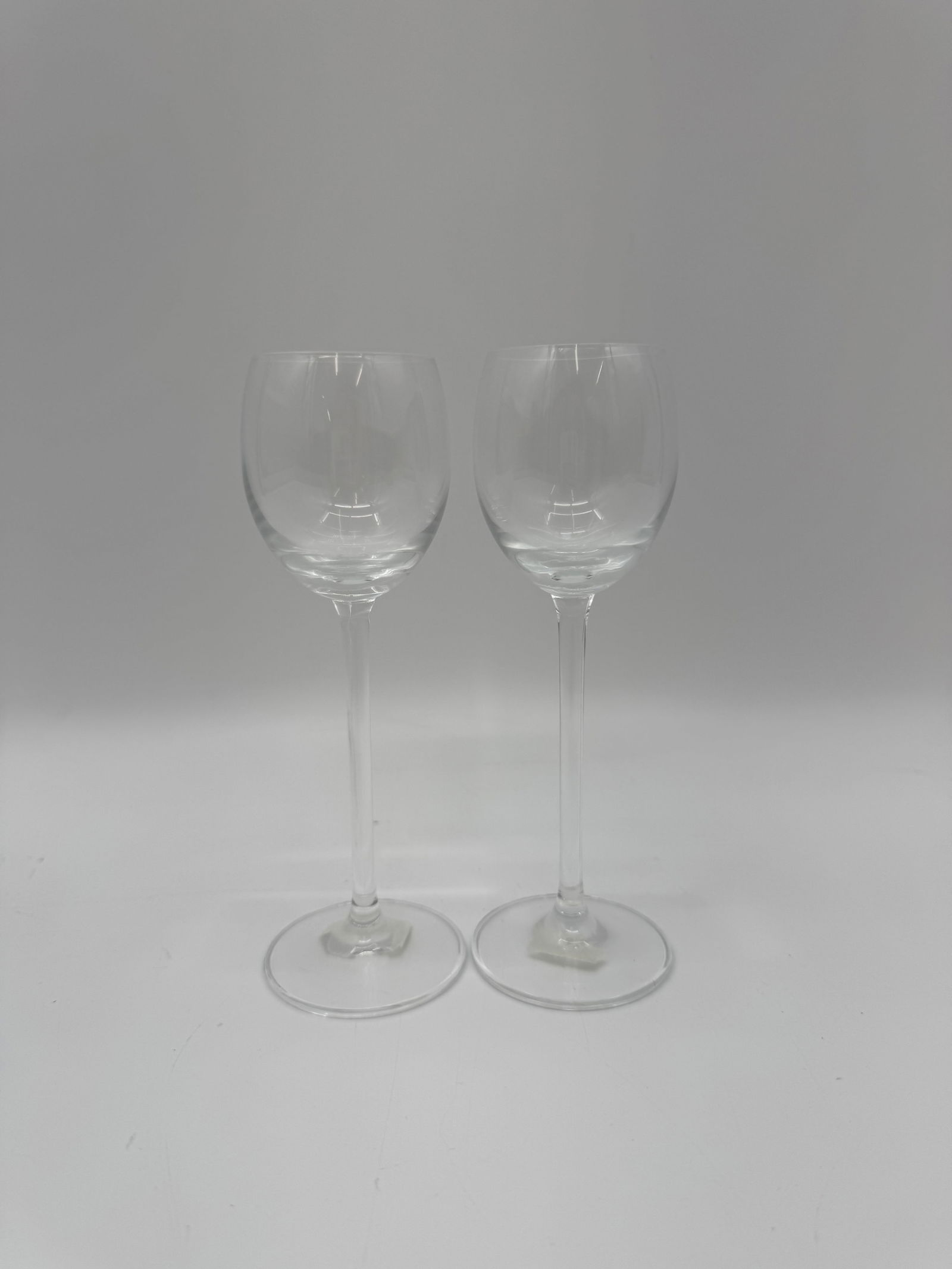 Pair of Tall Crystal Wine Glasses: Elegant pair of tall crystal wine glasses with slender stems and clear bowls. Timeless and refined design, perfect for formal dining or fine wine service.