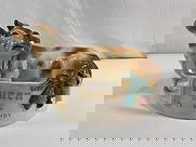 Tuaca Demi Milk Brandy Advertising - Box 11: A vintage ceramic advertising trinket featuring a reclining cow, promoting Tuaca Italian Brandy as "Milk Brandy." The detailed hand-painted design includes a lifelike brown and white