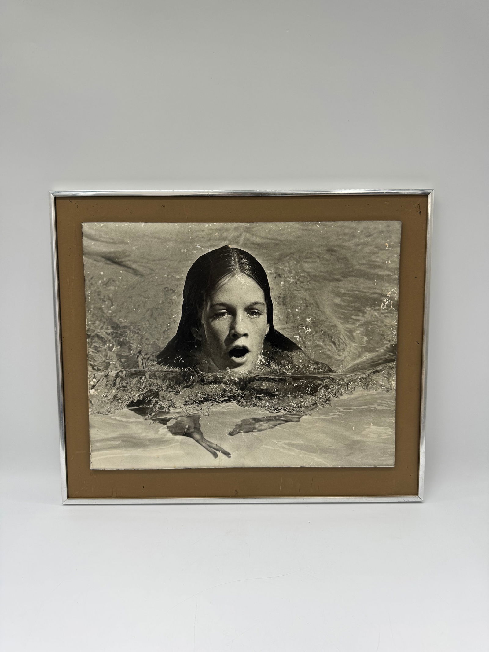 Framed B&W Photograph of Woman in Water: Black and white photograph of a woman in water, framed. Image size approximately 23.5 x 20 inches. Silver tone metal frame with brown inner border. Ready to hang.