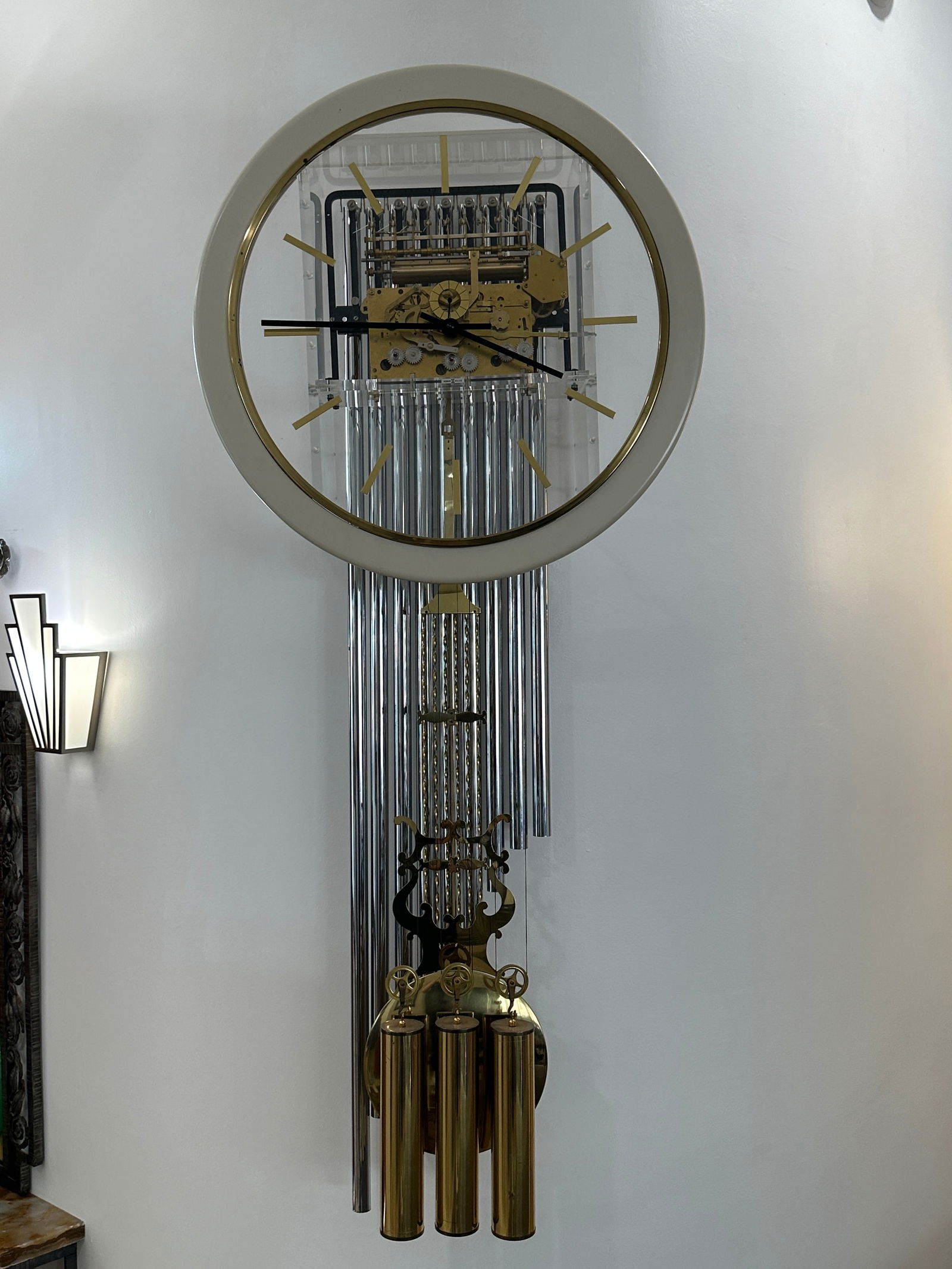 Howard Miller Tubular Chime Focal Point Wall Clock: This Howard Miller Focal Point wall clock features an elegant open-frame design with exposed brass-finished movement and long polished tubular chimes, creating a striking visual and acoustic presence.