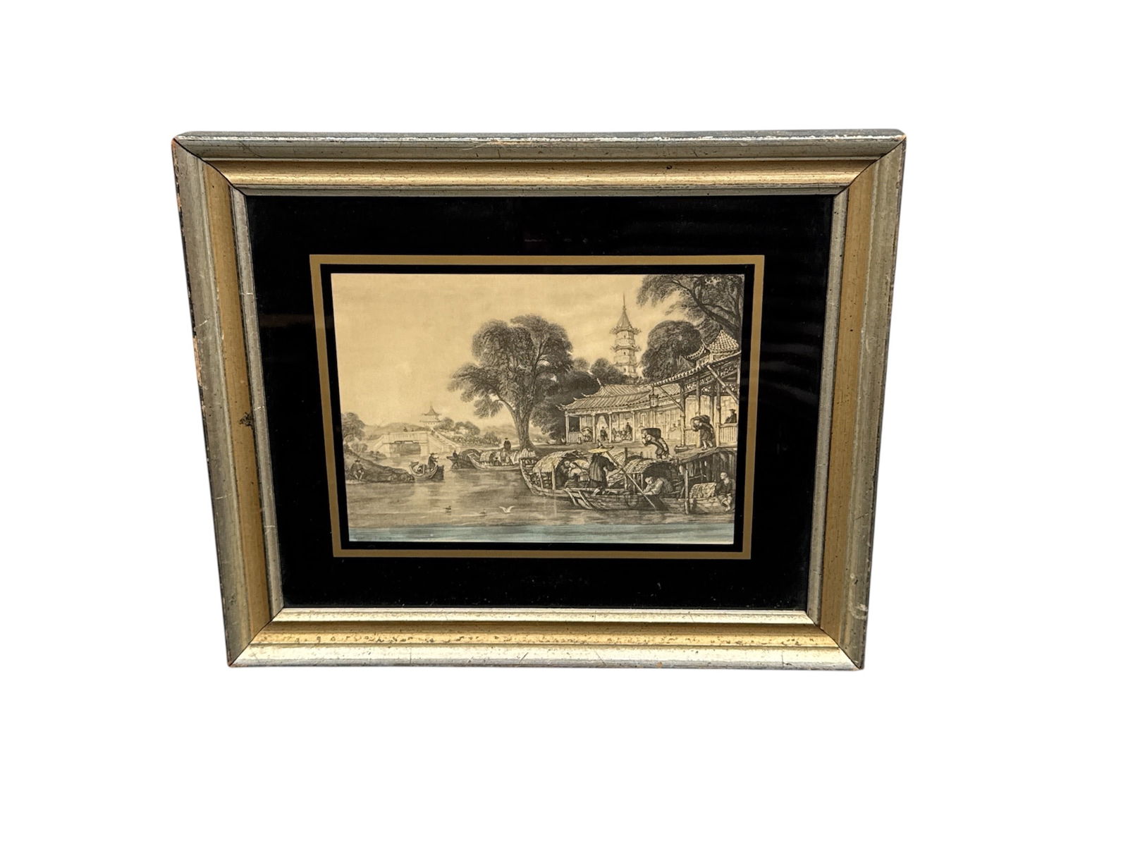 Framed Pastoral Village Scene Print: This framed print depicts a lively pastoral village scene with figures gathered along a riverbank, animals in motion, and cottages nestled among trees in the background. The composition captures a