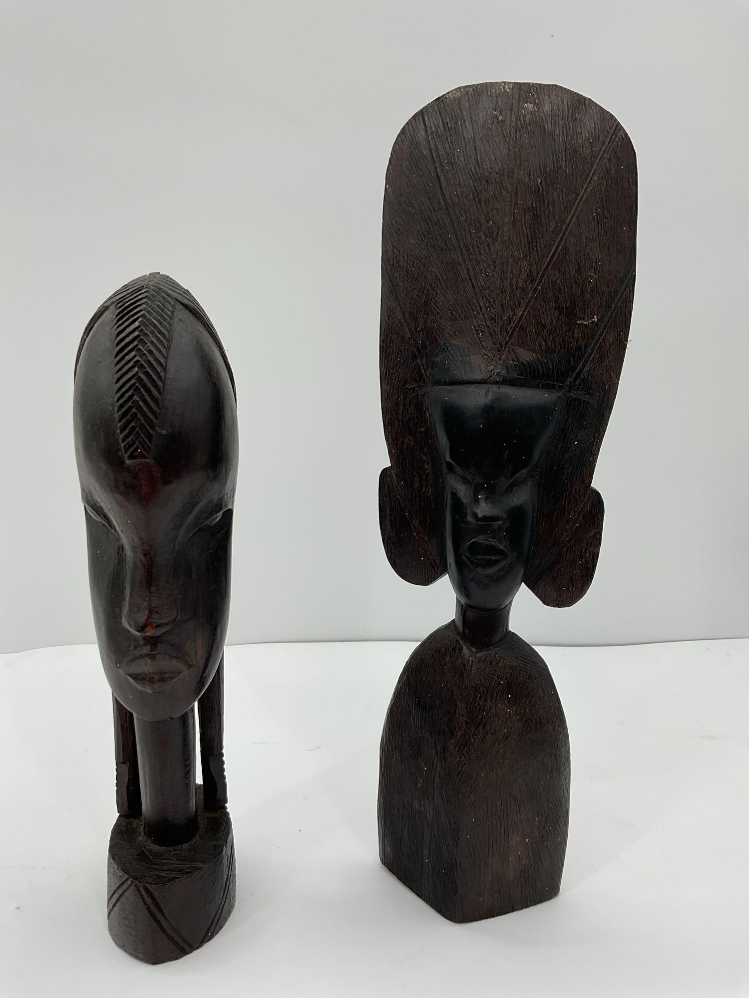 Hand-Carved African Tribal Busts - Box 4: A pair of hand-carved African tribal bust sculptures, each displaying unique facial features and intricate detailing. The sculptures are made from dark hardwood, with expressive faces and stylized elo