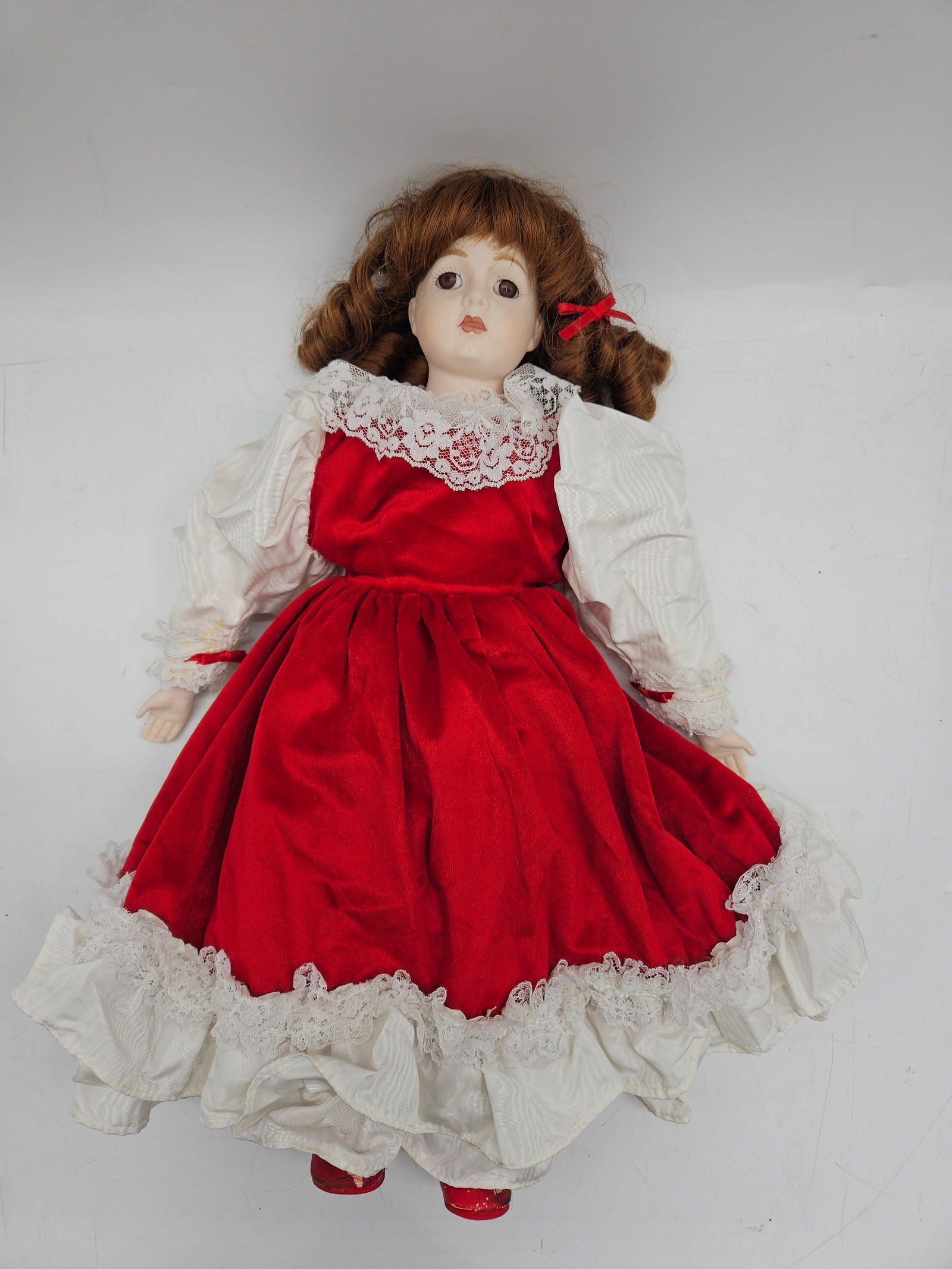 Royal Standard 1987 Porcelain Doll in Red Dress: Royal Standard 1987 porcelain doll featuring a red dress with white lace trim and matching shoes. Measures approximately 20 inches in height and 12 inches at its widest point.