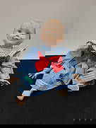 Porcelain Doll in Sailor Suit: Porcelain doll with painted features, dressed in a blue sailor suit with a red bow. Measures approximately 9 inches high, 10 inches wide at the widest part, and 5 inches deep.