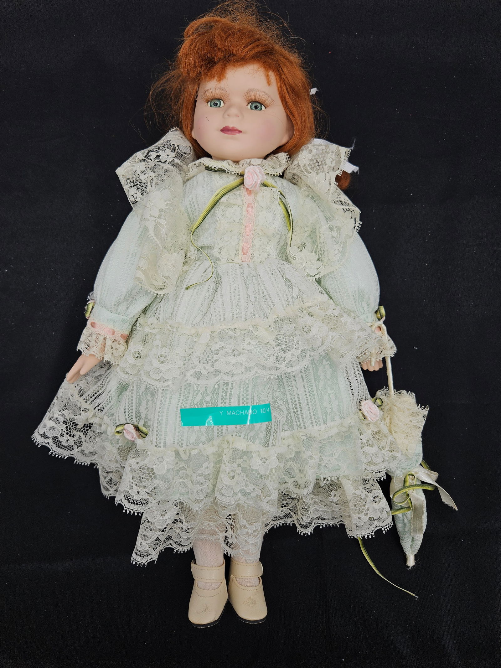 Porcelain Doll with Lace Dress and Parasol: Porcelain doll with red hair and blue eyes, wearing a light blue and lace dress with matching parasol. Stands approximately 17 inches tall.