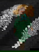 Porcelain Doll with Blonde Hair in Green Floral Dress: Vintage porcelain doll with painted facial features, curly blonde hair, and a green floral dress with sailor-style collar and blue ribbon bow. Includes white stockings and shoes. Light age wear to