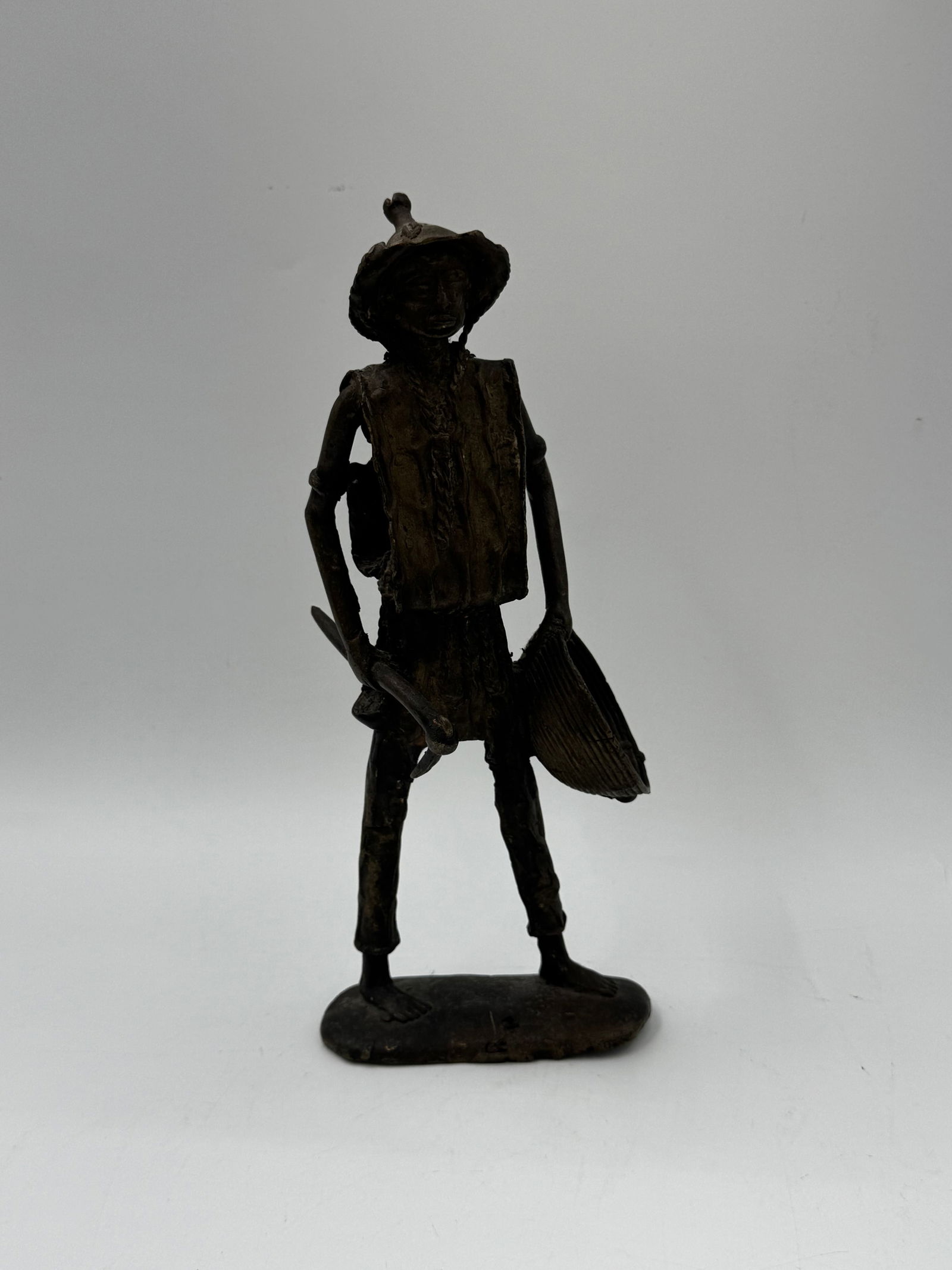 Metal Folk Art Figure of a Man with Pan: Metal folk art sculpture depicting a man with a hat and pan. The figure is mounted on a rectangular base. Dimensions: 12x5x4 inches.