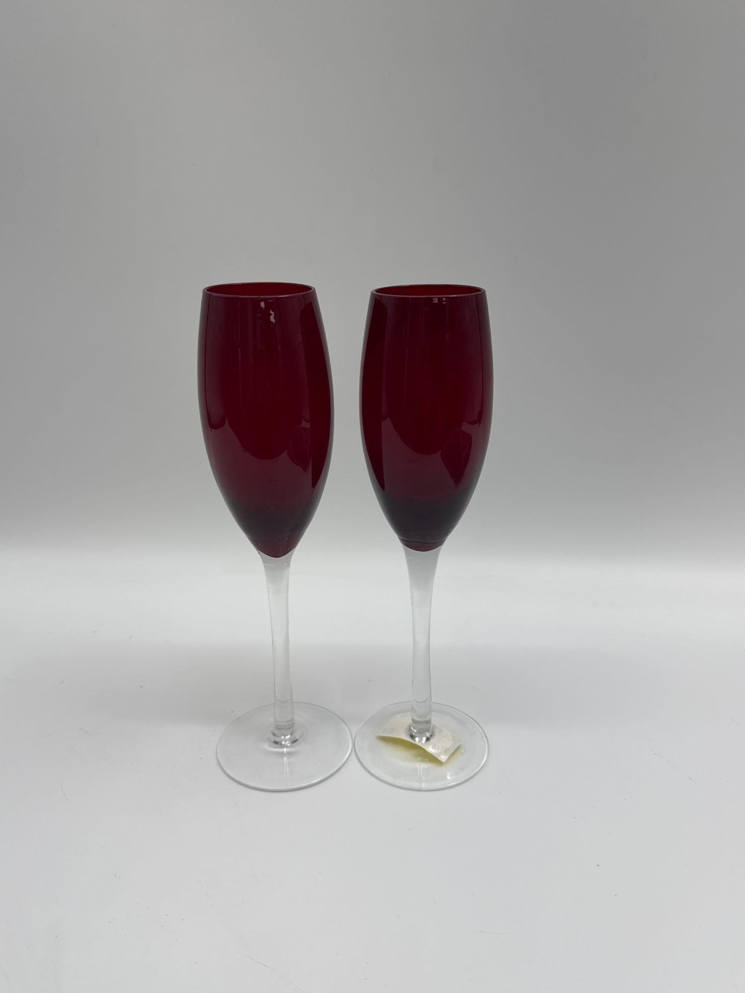 Pair of Ruby Red Champagne Flutes: Elegant set of two champagne flutes with deep ruby red bowls and clear glass stems and bases. A stylish addition for special occasions, these glasses combine modern simplicity with a touch of vintage