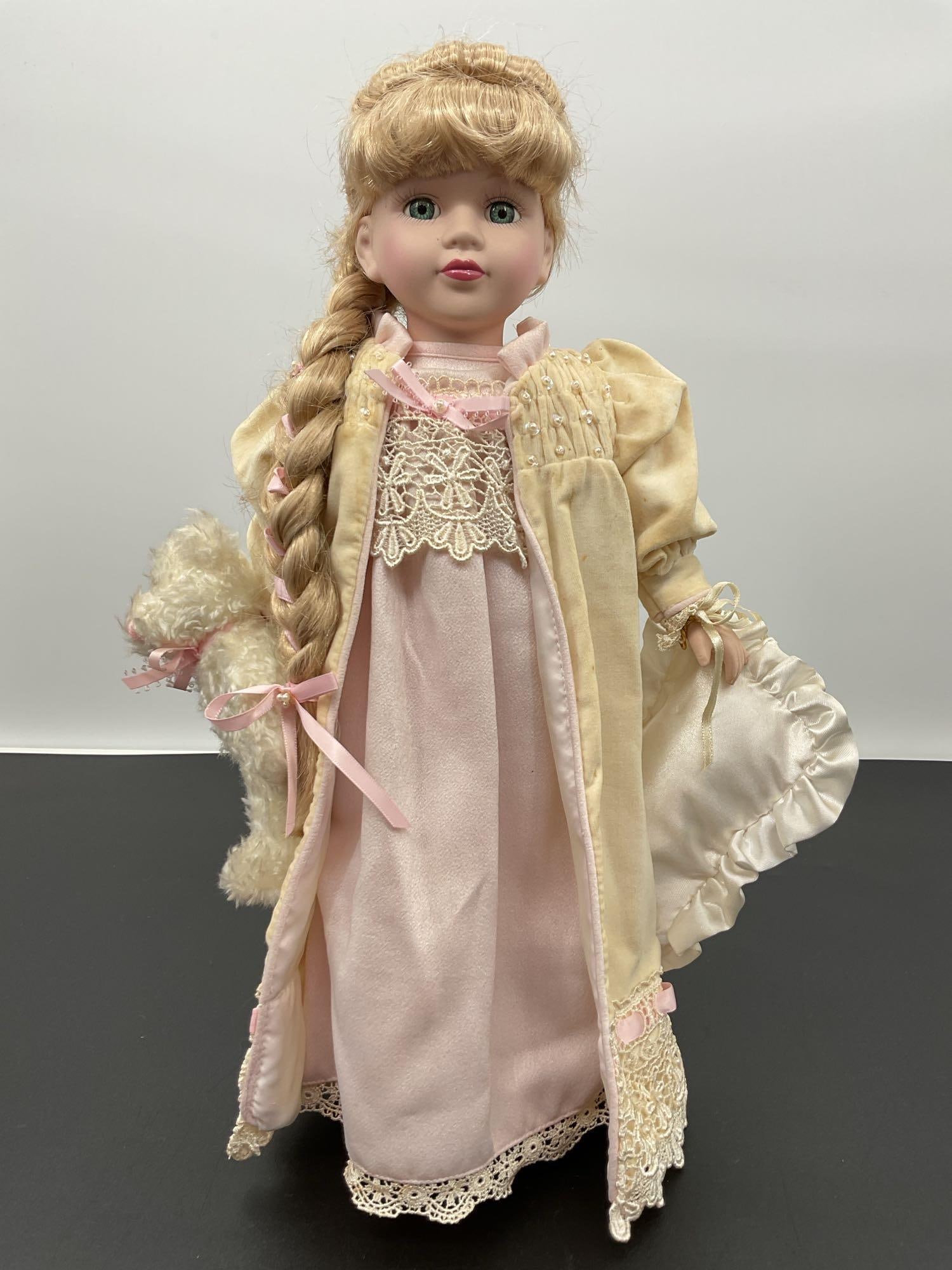 Porcelain Doll in Nightgown with Teddy Bear: This porcelain doll features long blonde hair styled in a thick braid with pink ribbon accents. She wears an elegant pale pink nightgown with a cream satin robe trimmed in lace and pearls. The outfit