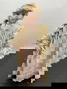 Porcelain Doll in Nightgown with Teddy Bear: This porcelain doll features long blonde hair styled in a thick braid with pink ribbon accents. She wears an elegant pale pink nightgown with a cream satin robe trimmed in lace and pearls. The outfit