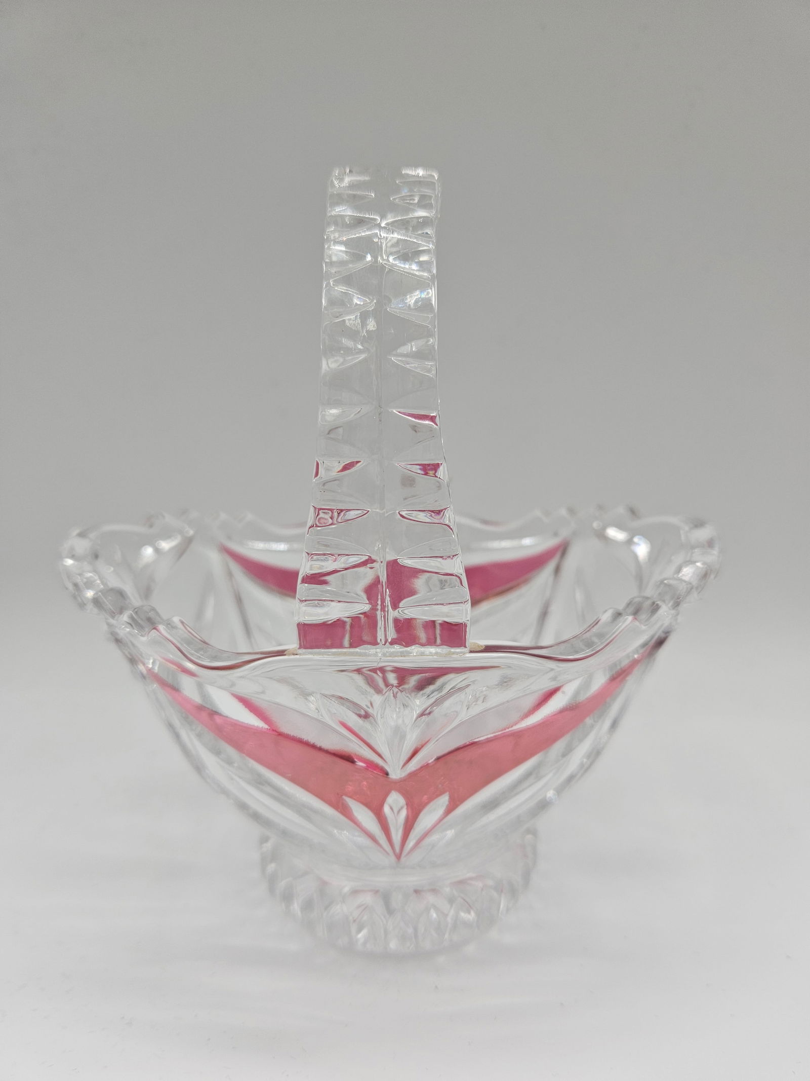 Cut Crystal Basket with Ruby Flashes: Cut crystal basket featuring ruby flashed accents. The basket has a scalloped rim and a decorative handle. Dimensions: H: 7in W: 6in L: 4in